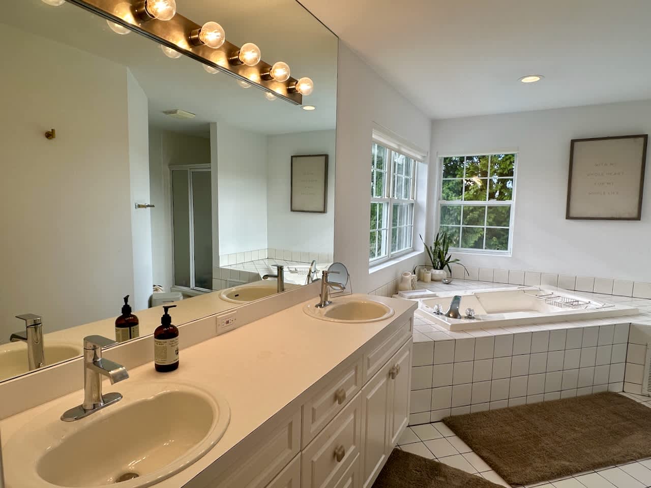 Primary bathroom with a double vanity, backlit mirror, and jetted soaking tub.