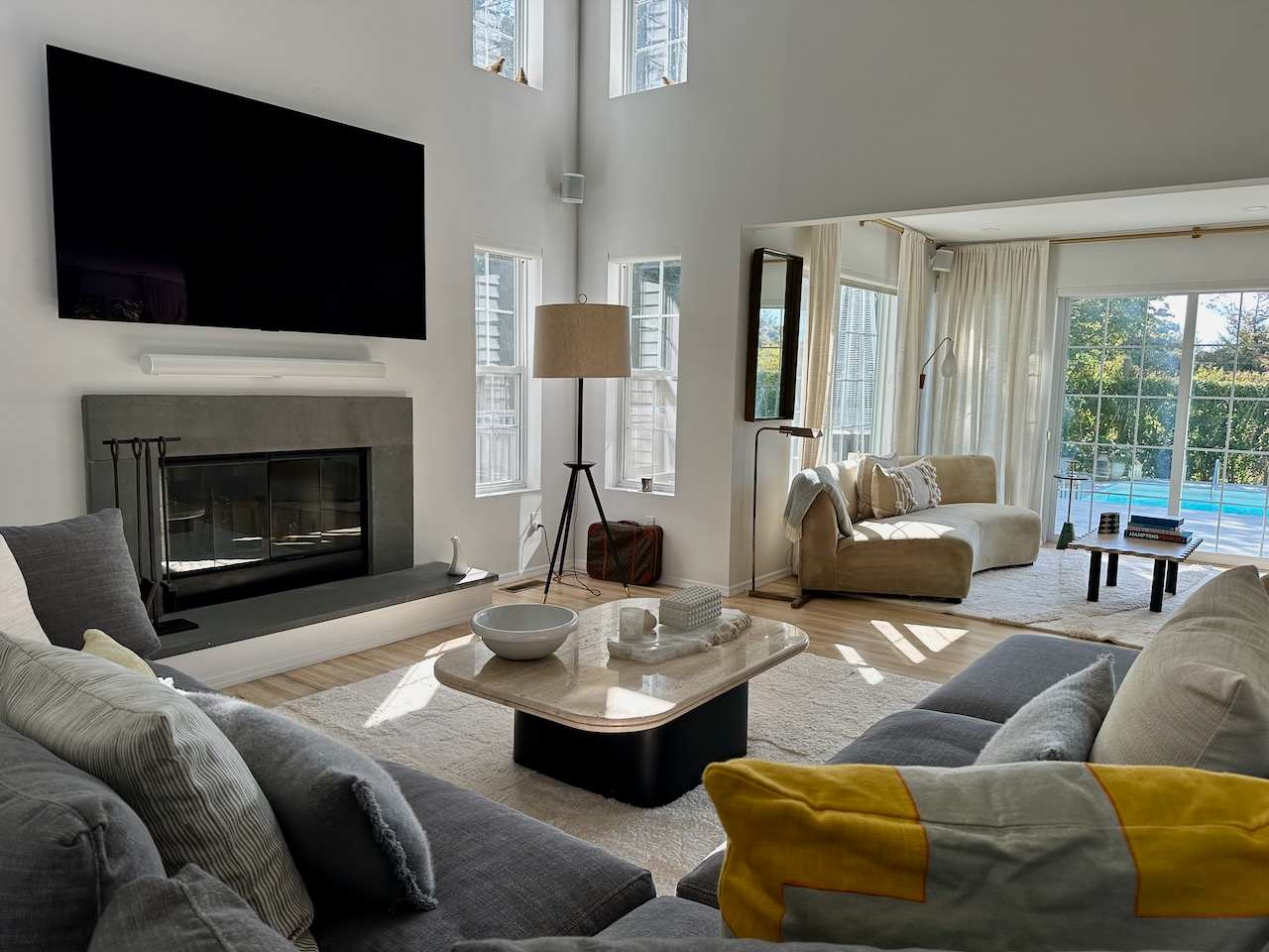 Living room with gray sectional seating, fireplace, and sliding glass doors opening toward the pool.