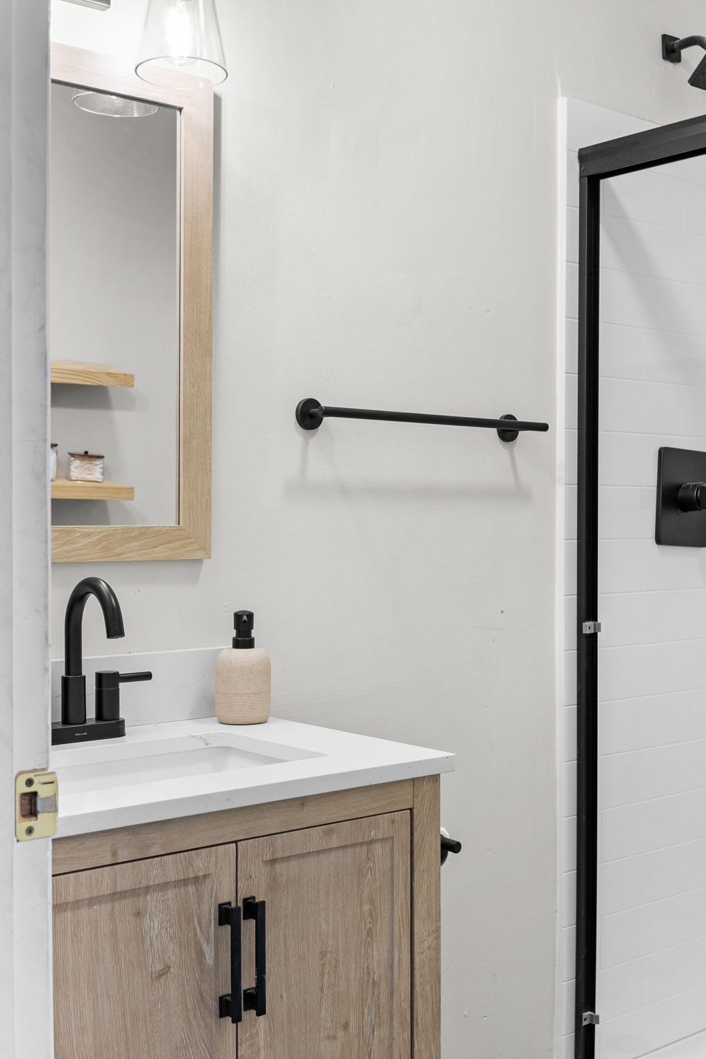 Sleek & Modern Bathroom Space – A stylish bathroom featuring a black faucet, wood-accented vanity, and bright lighting for a fresh and elegant touch.