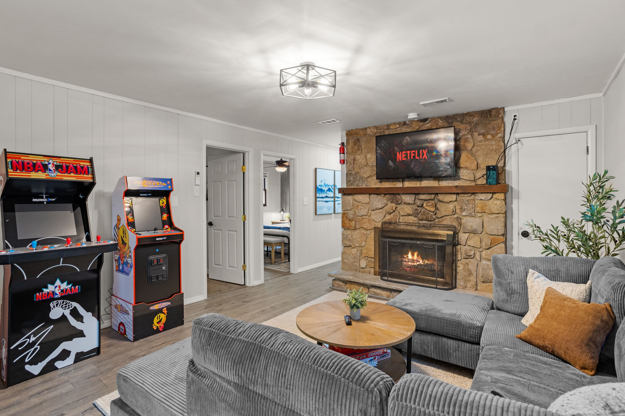 A dedicated entertainment space with classic arcade machines, bar seating, and framed artwork, adding a nostalgic touch.