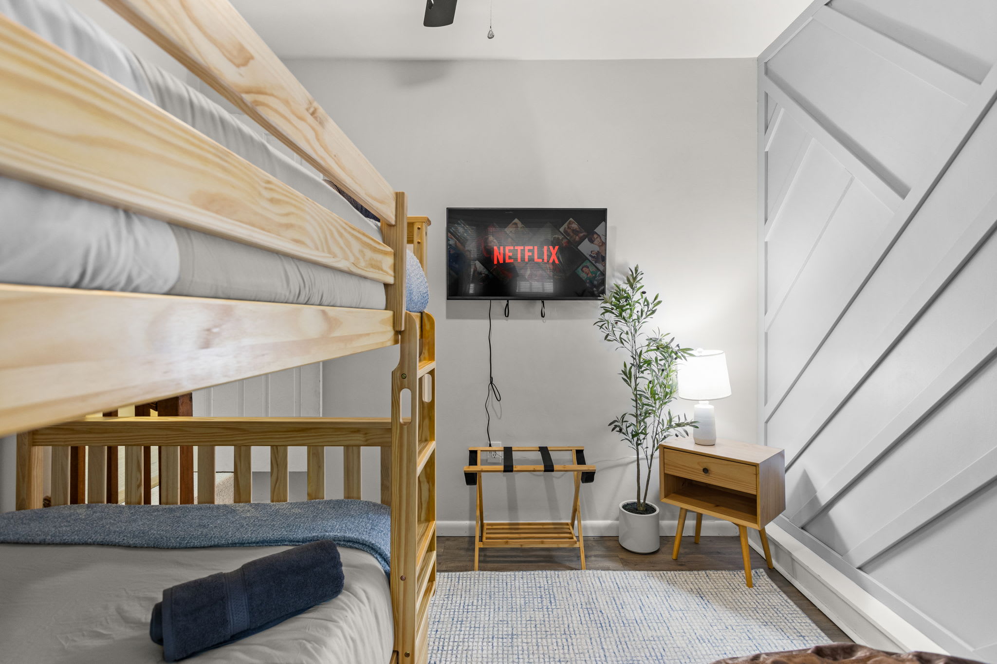 Modern Bunk Room with Cozy Vibes – A stylish bunk room featuring wood accents, a mounted TV, and soft lighting, making it a perfect space for kids or groups.