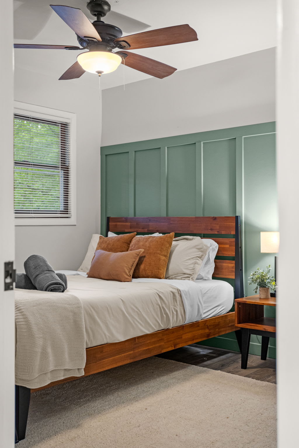  A warm and inviting bedroom featuring a wooden bed frame, neutral bedding, and a modern paneled accent wall.