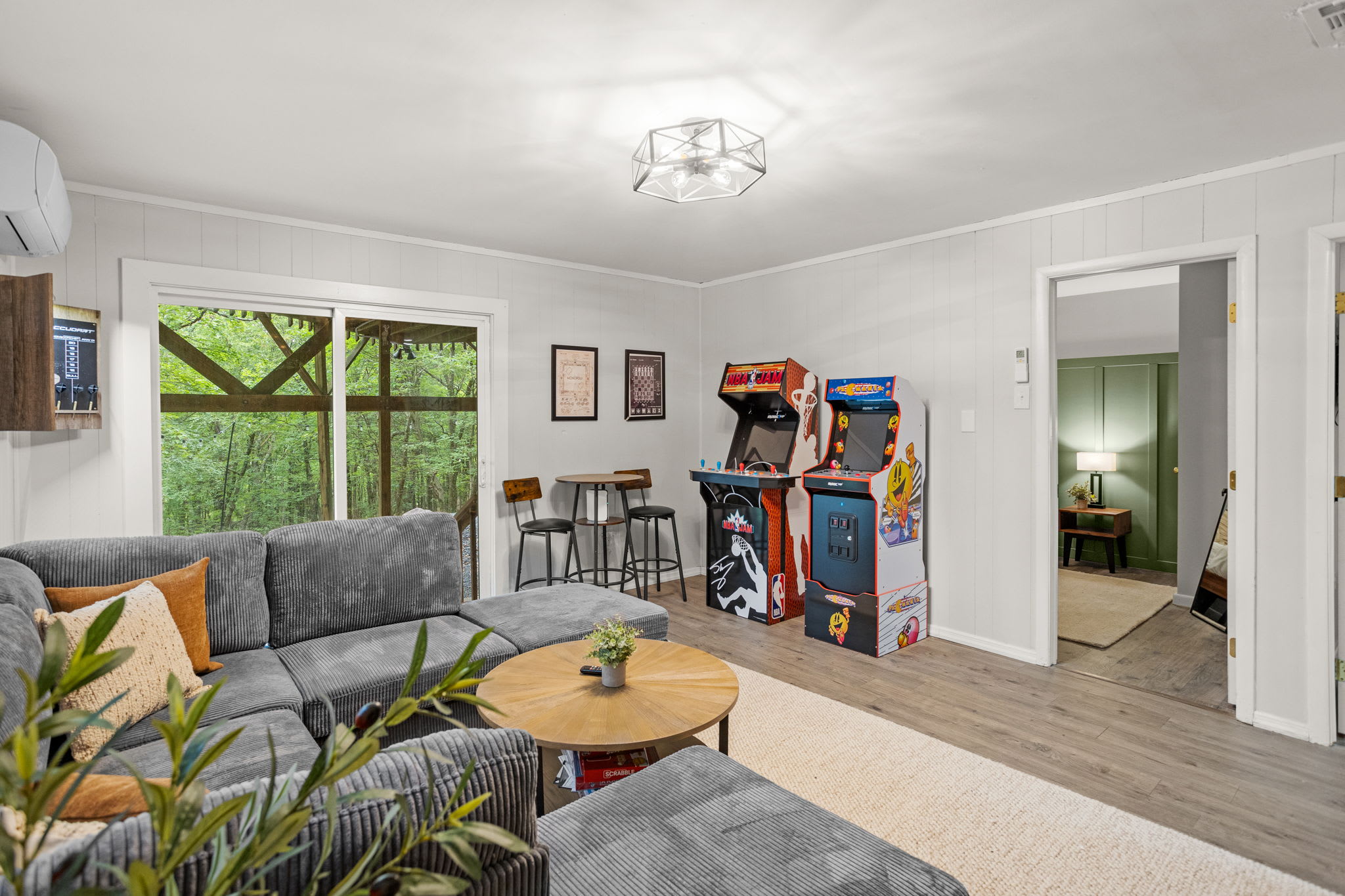 Spacious & Bright Lounge Area – A comfortable and inviting living space with ample seating, an arcade game, and large windows bringing in natural light.