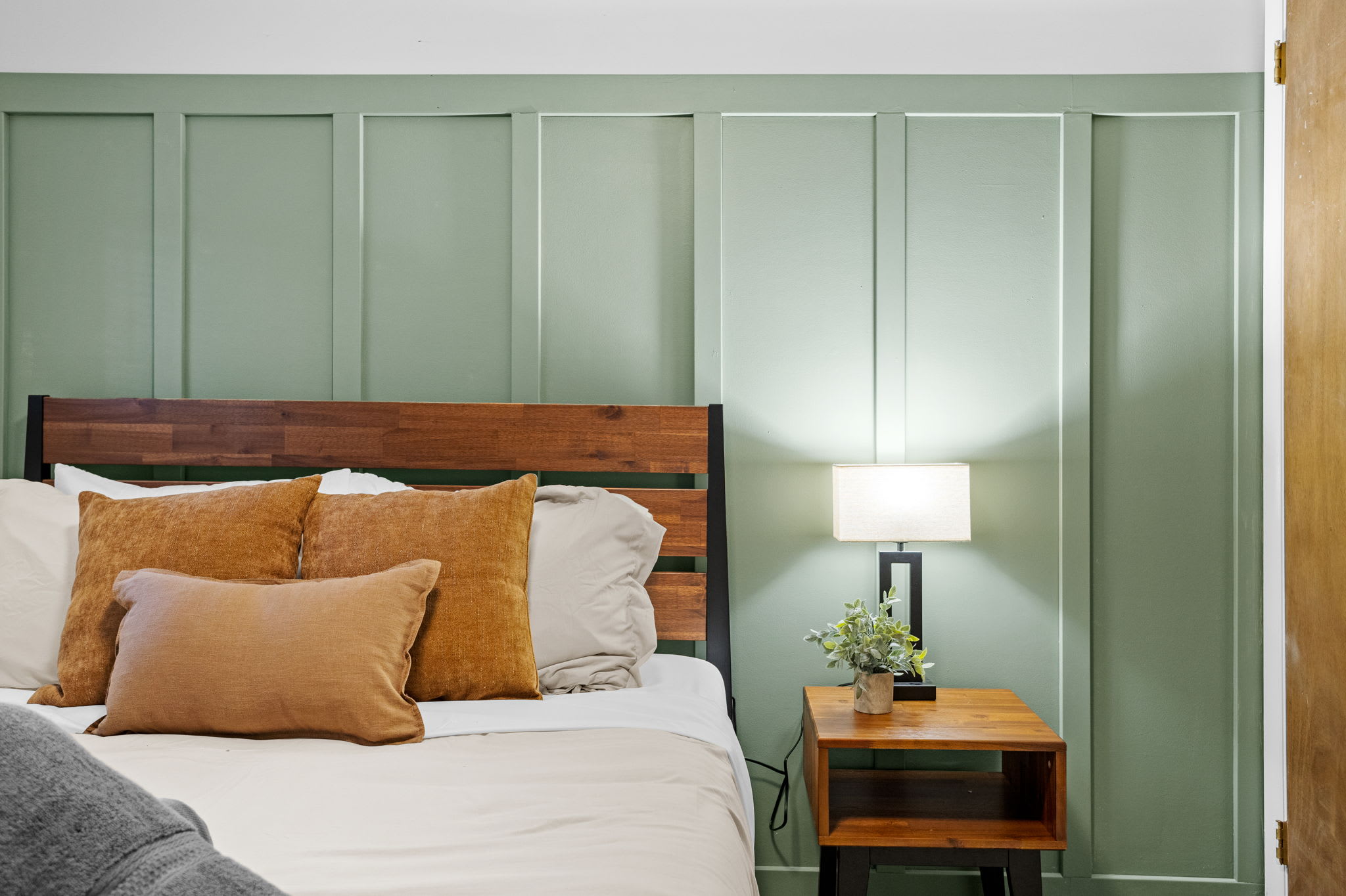 A well-decorated bedroom with a paneled wall, wooden nightstands, and a balanced mix of textures for a restful atmosphere.