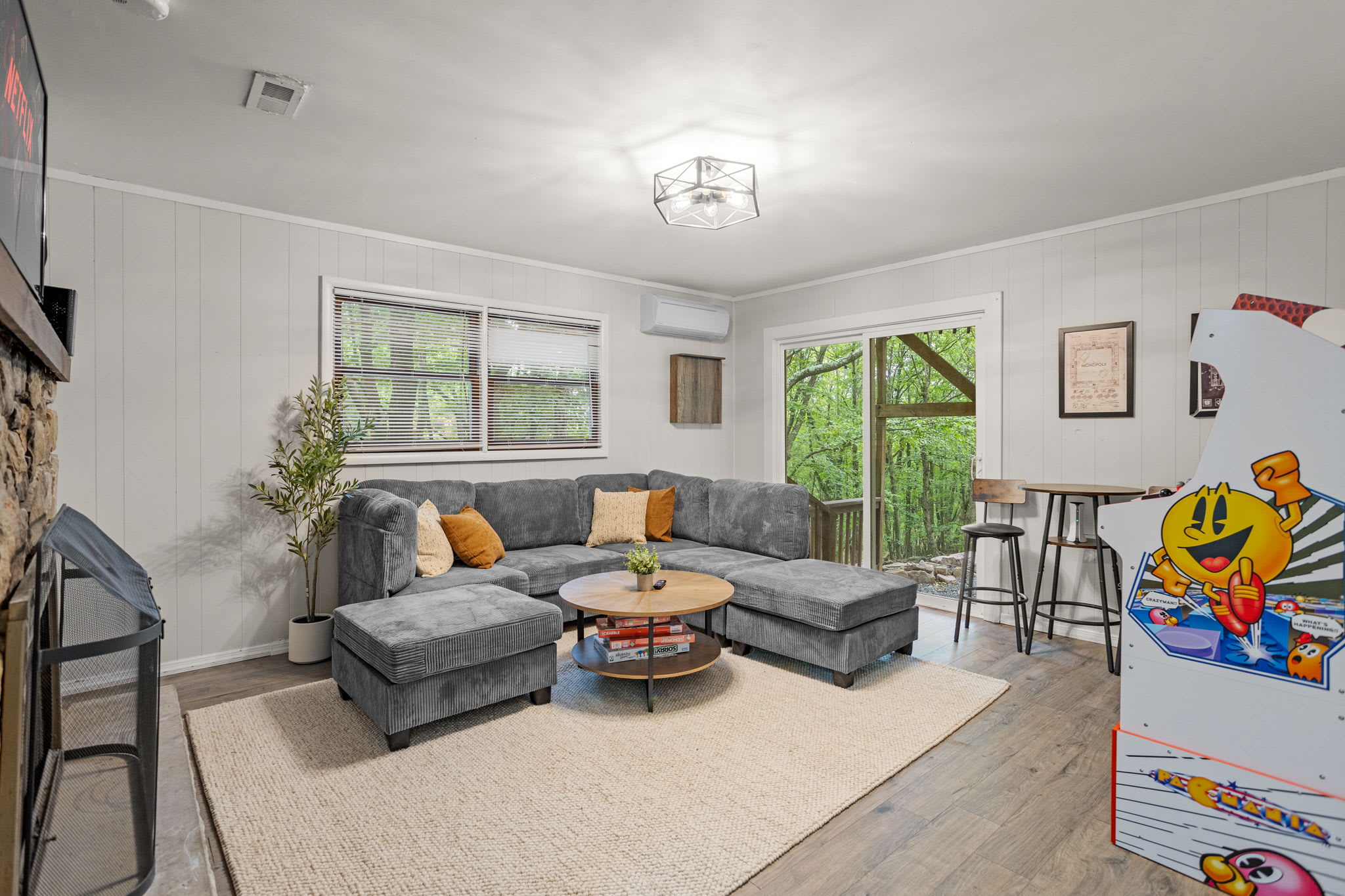 Bright & Open Living Space – A beautifully lit living area with comfortable sofas, elegant decor, and an arcade game machine for added entertainment.