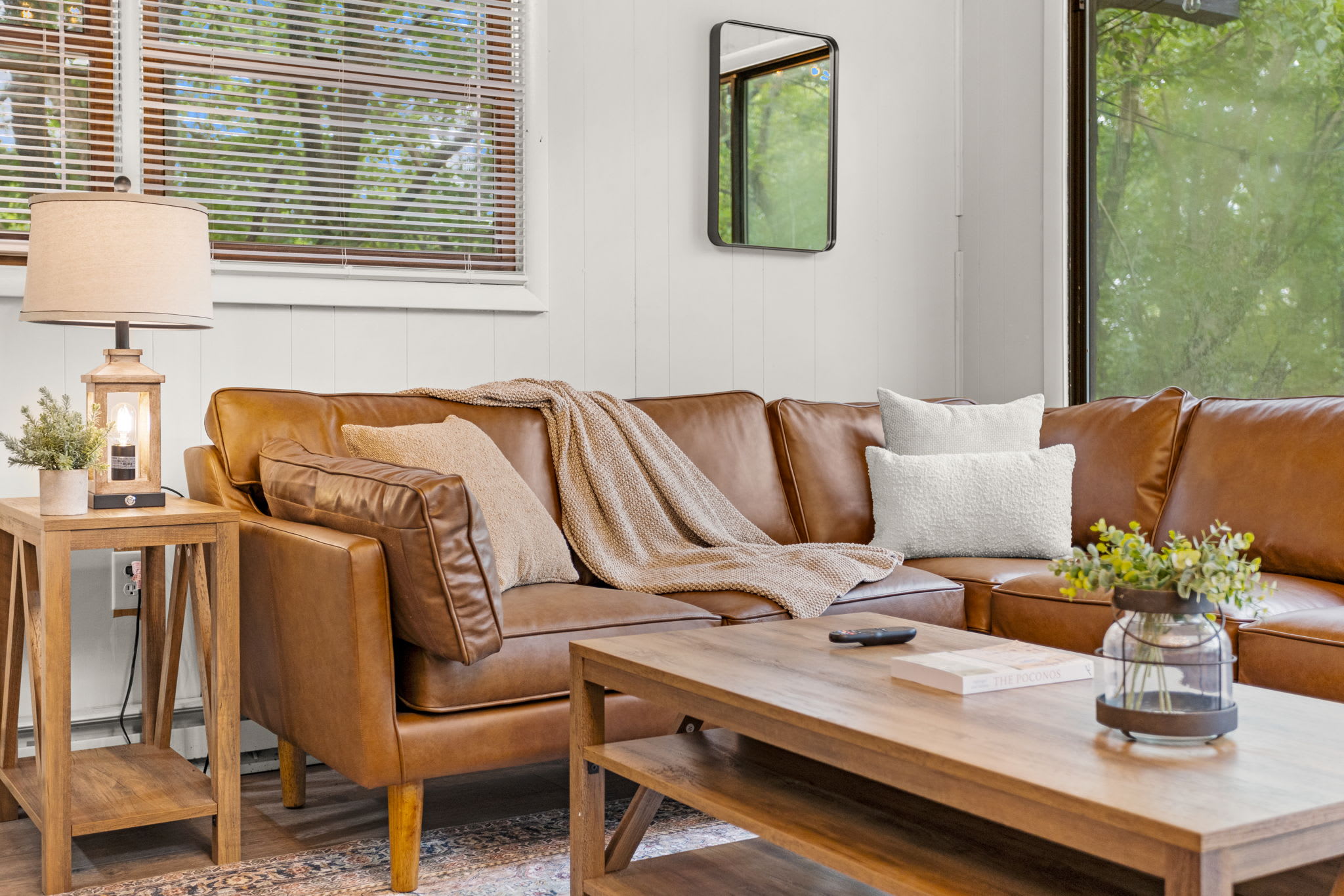 Cozy Living Space – A bright and inviting living area with a stylish leather sofa, modern decor, and large windows bringing in natural light.