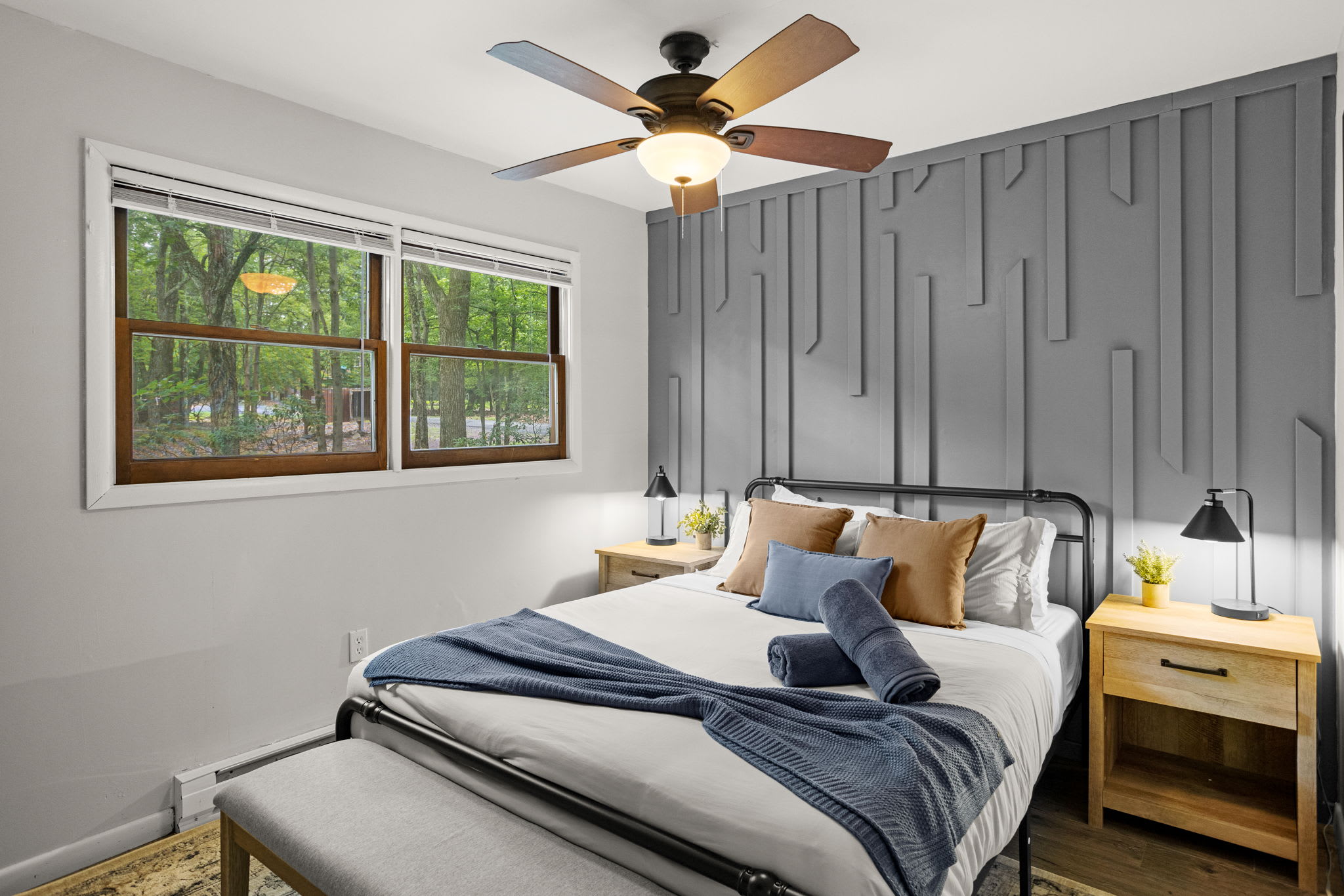 A cozy room with a textured accent wall, nightstand lighting, and neatly folded towels for a luxurious touch.