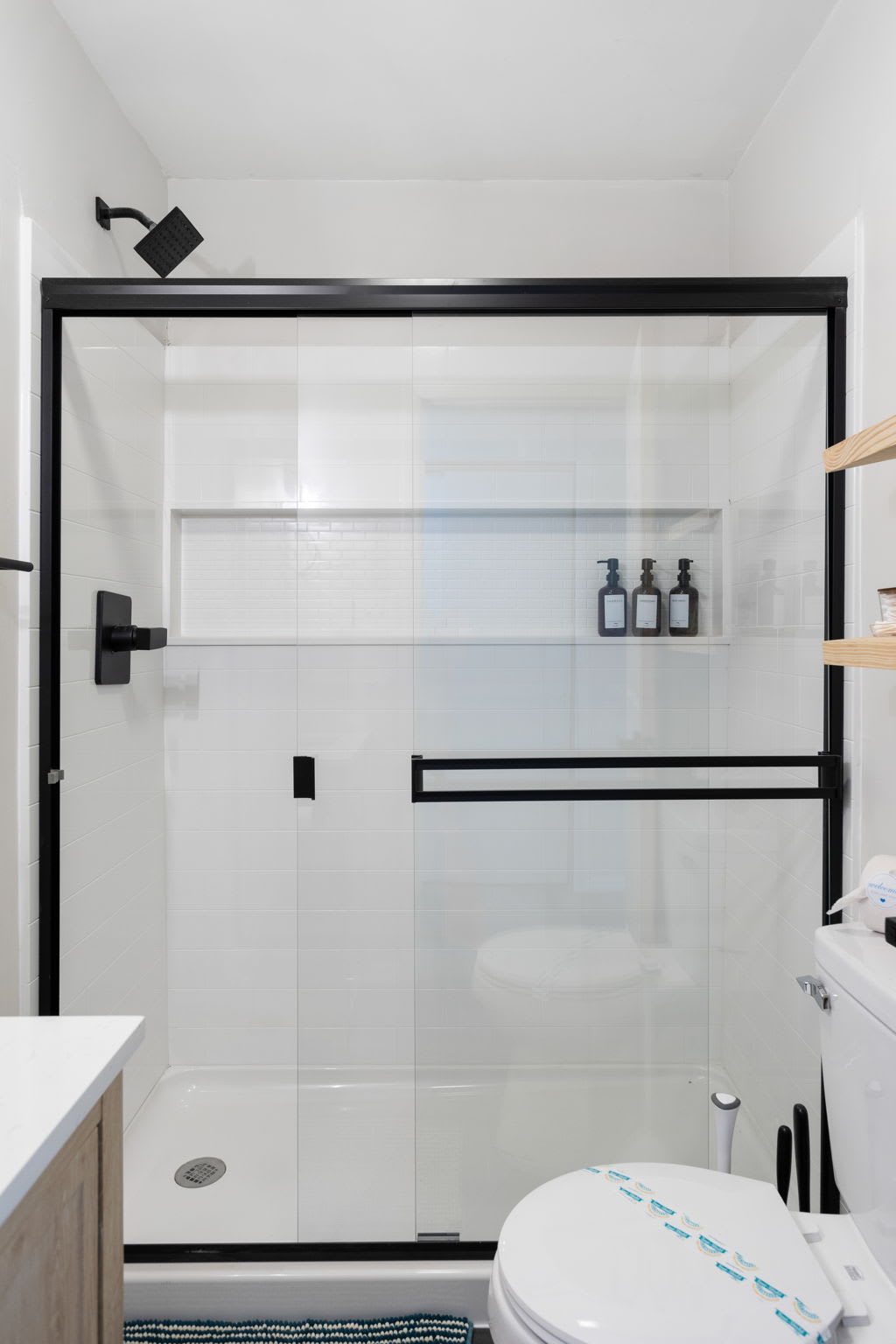 Luxurious Glass Shower – A modern glass-enclosed shower with black fixtures and built-in shampoo dispensers.