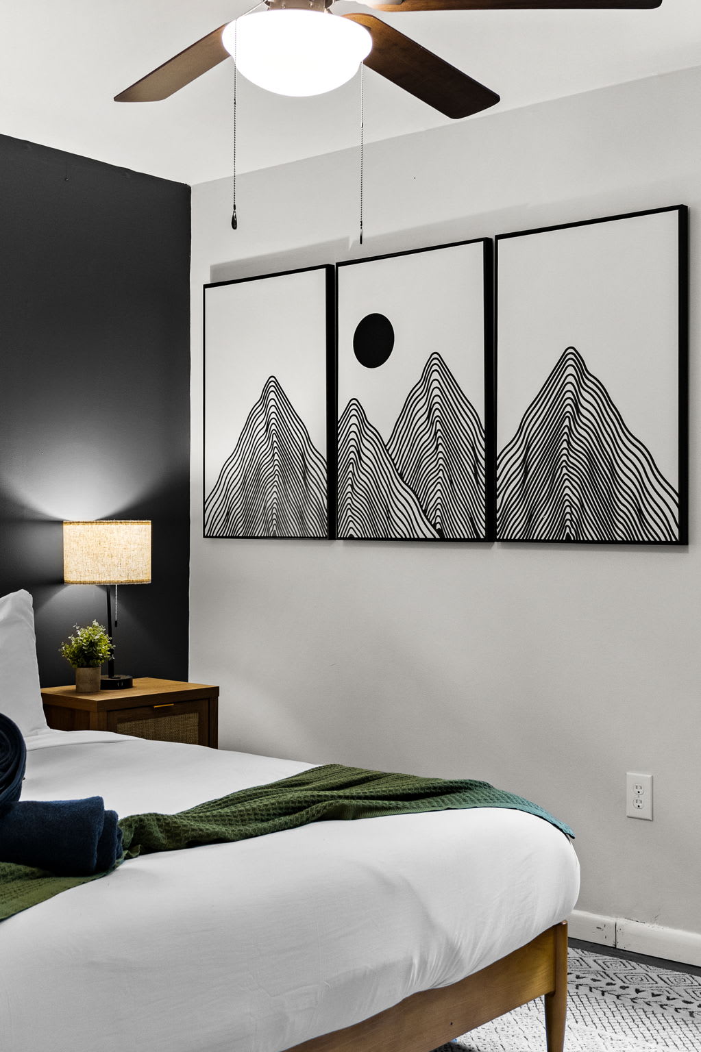 A stylish bedroom featuring a mountain-themed accent wall, soft bedding, and warm lighting.