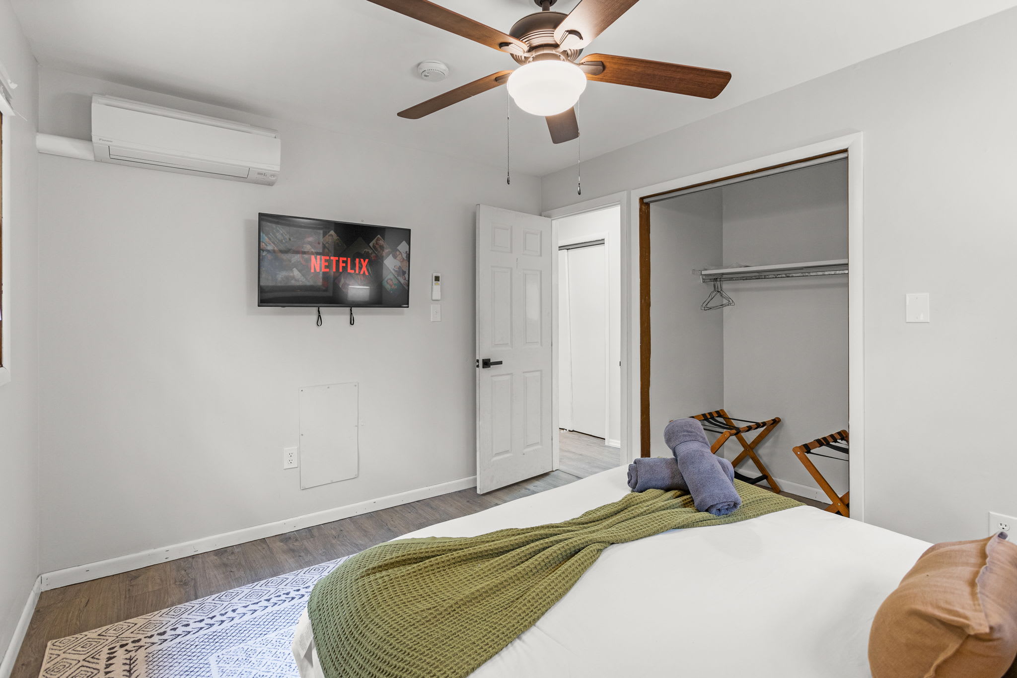 A spacious and serene room featuring a soft color palette, a mounted TV, and warm-toned decor for a cozy retreat.