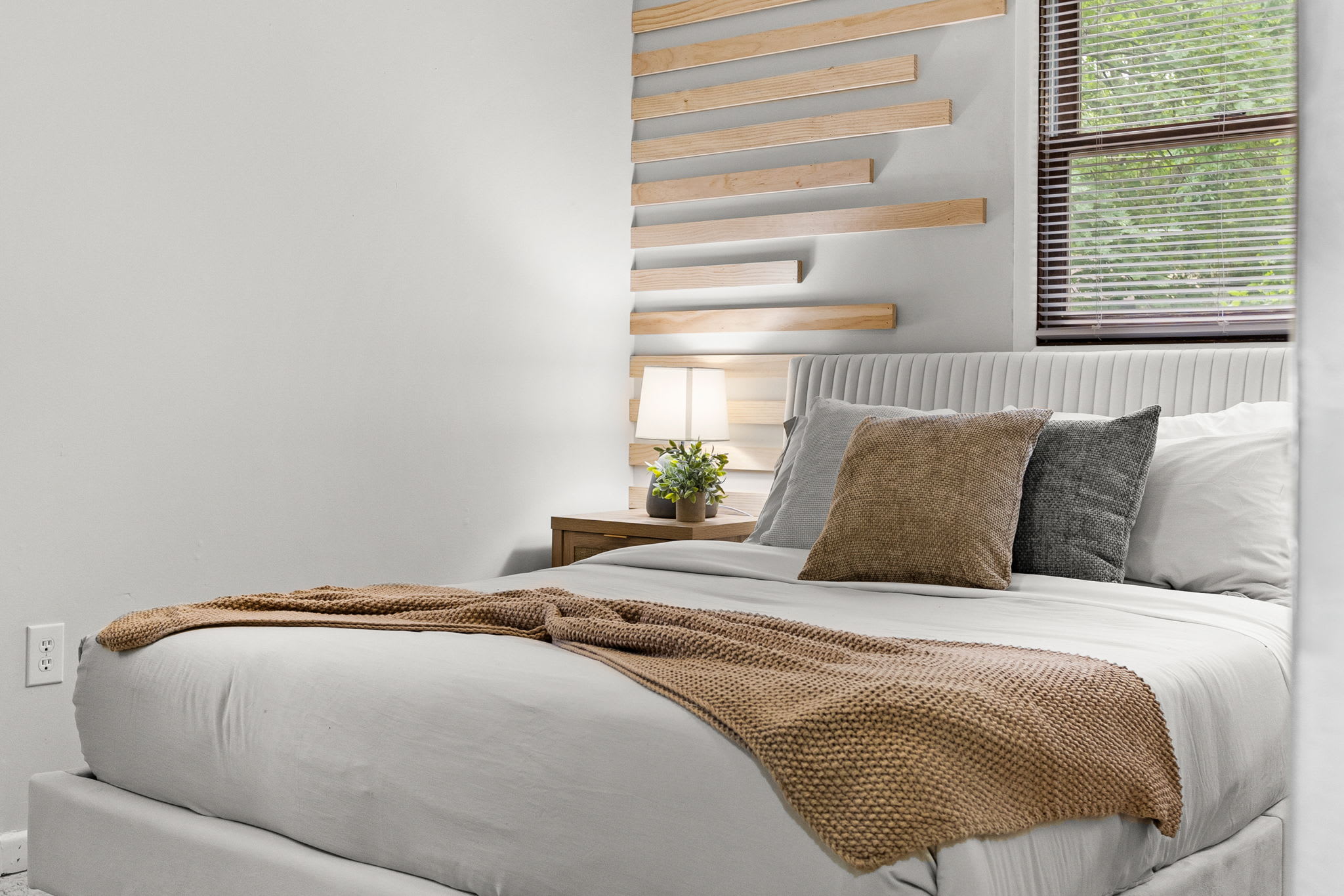 A detailed look at the stylish bed setup, with decorative pillows and wooden accent wall shelves adding charm.