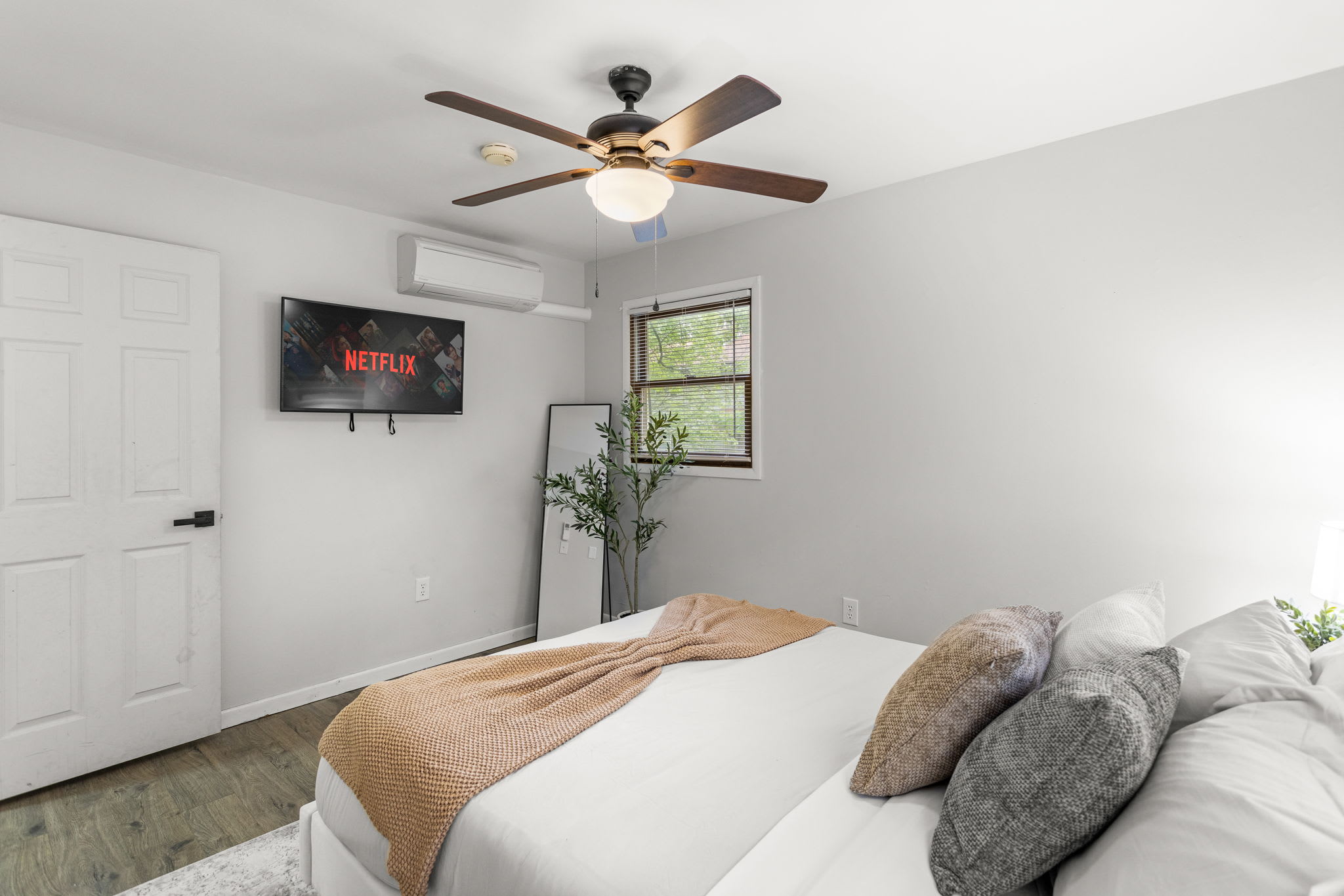A closer look at the bedding, ceiling fan, and mounted TV, offering a modern yet cozy feel.