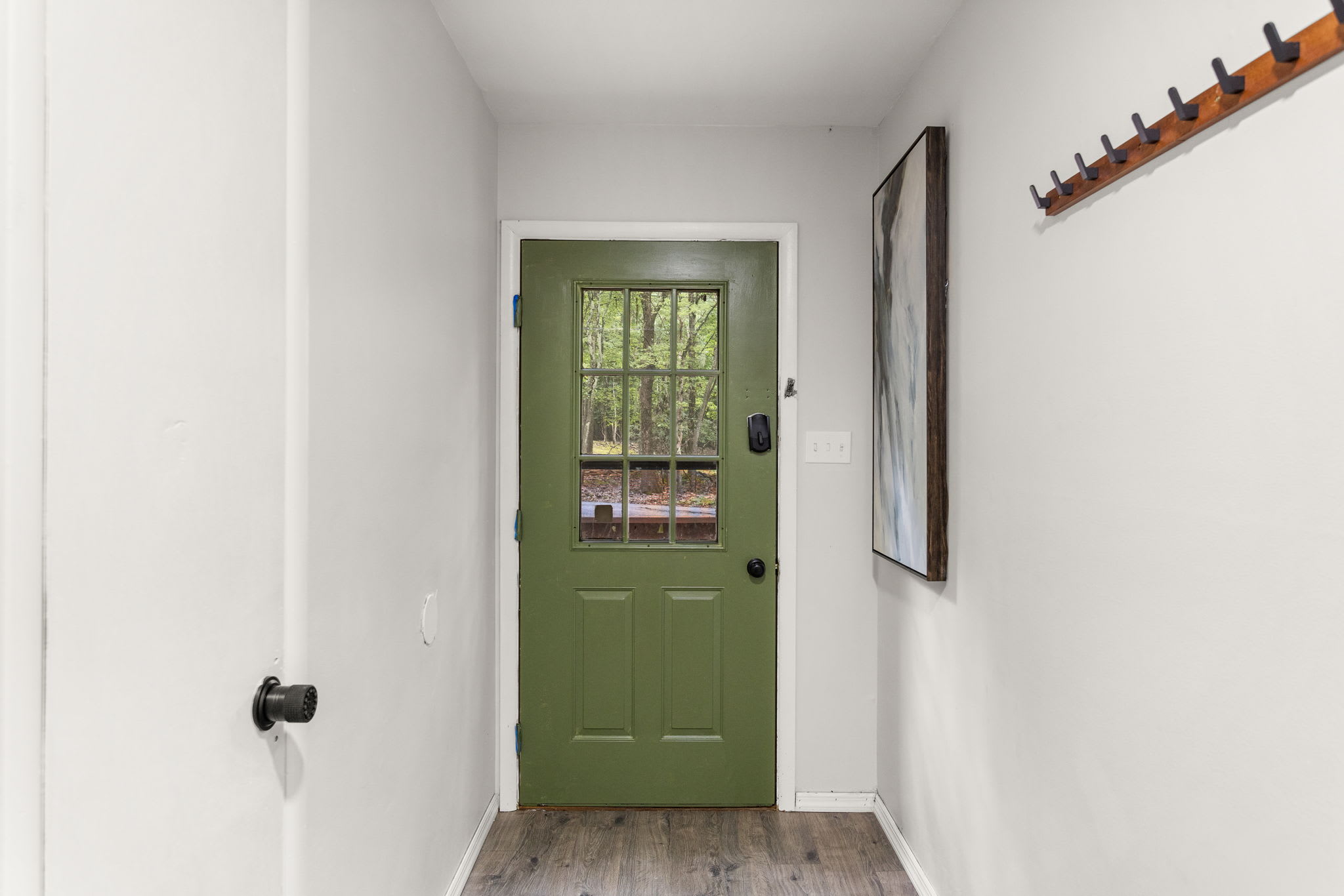 A charming entrance with a rustic green door and coat hooks, adding character to the home.