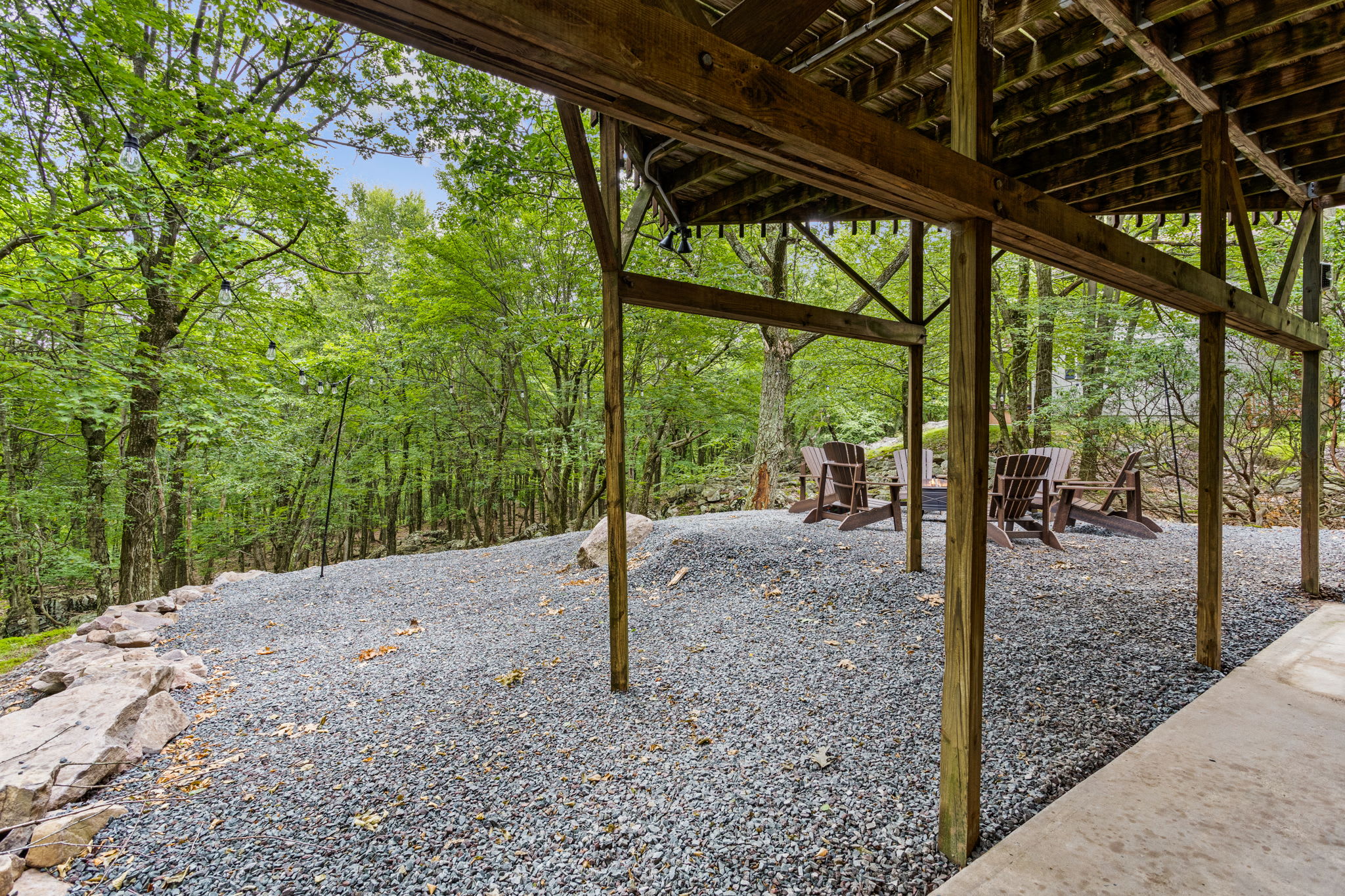 Under-Deck Hangout Space - A shaded relaxation area beneath the deck, providing extra seating in a tranquil, wooded setting.