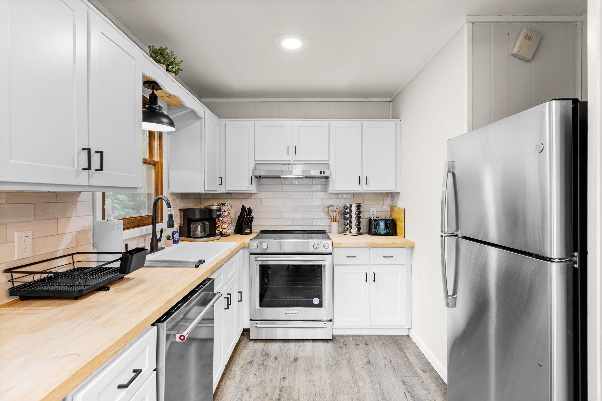 A spacious kitchen with white cabinets, butcher block countertops, and stainless steel appliances.