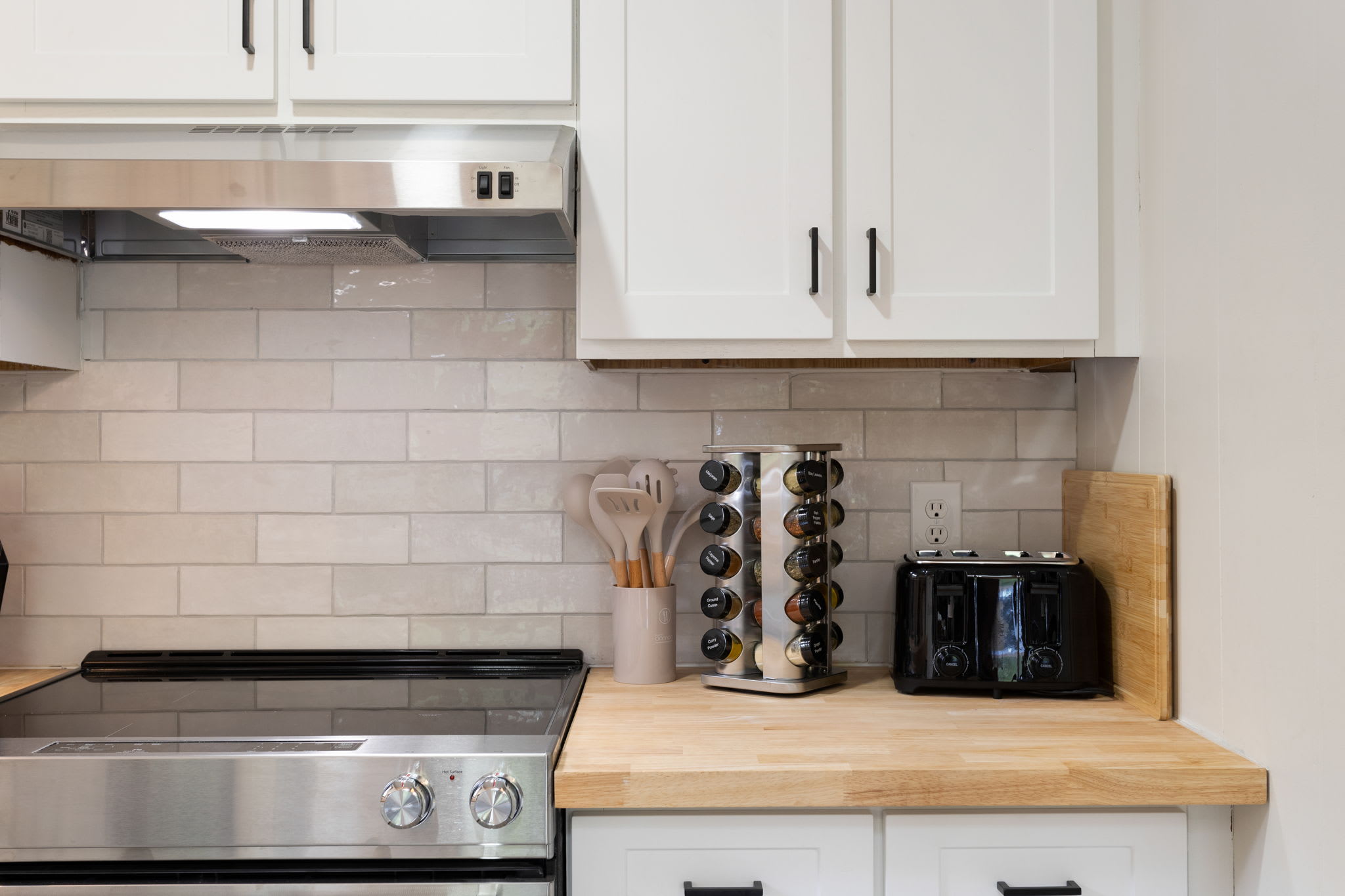 Minimalist Kitchen Close-Up – A sleek kitchen corner with a stovetop, spice rack, and neatly arranged countertop essentials.