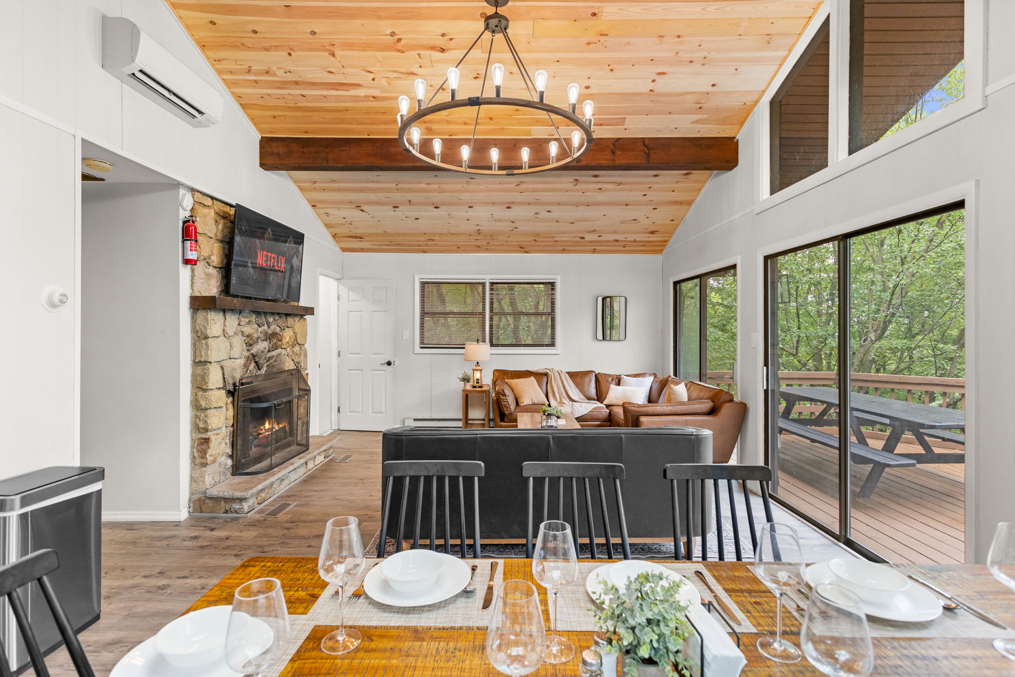  A grand space with vaulted ceilings, a fireplace, a chandelier, and a beautifully set dining table.