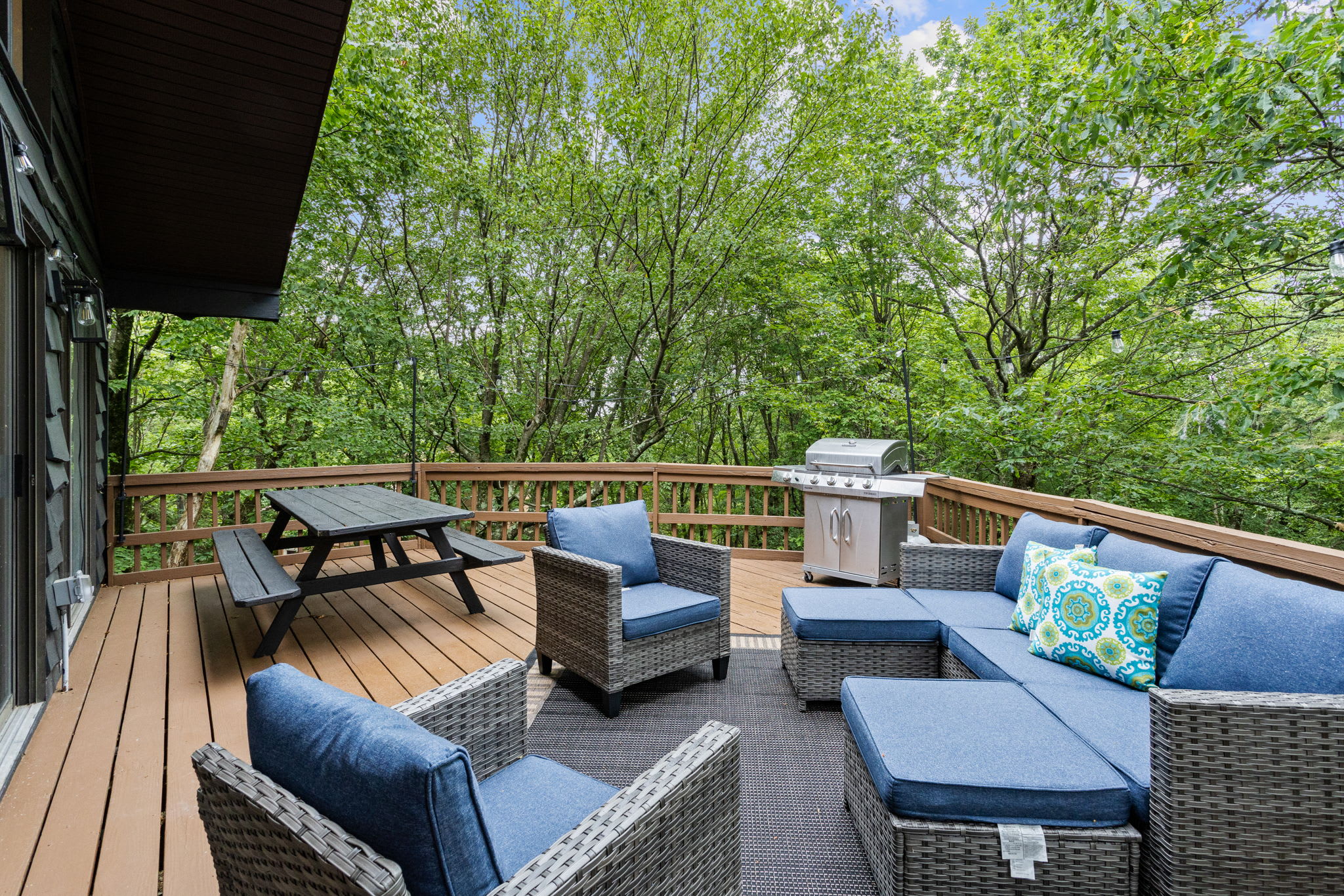 A peaceful deck setup with deep blue cushions and a fire pit, perfect for relaxation.