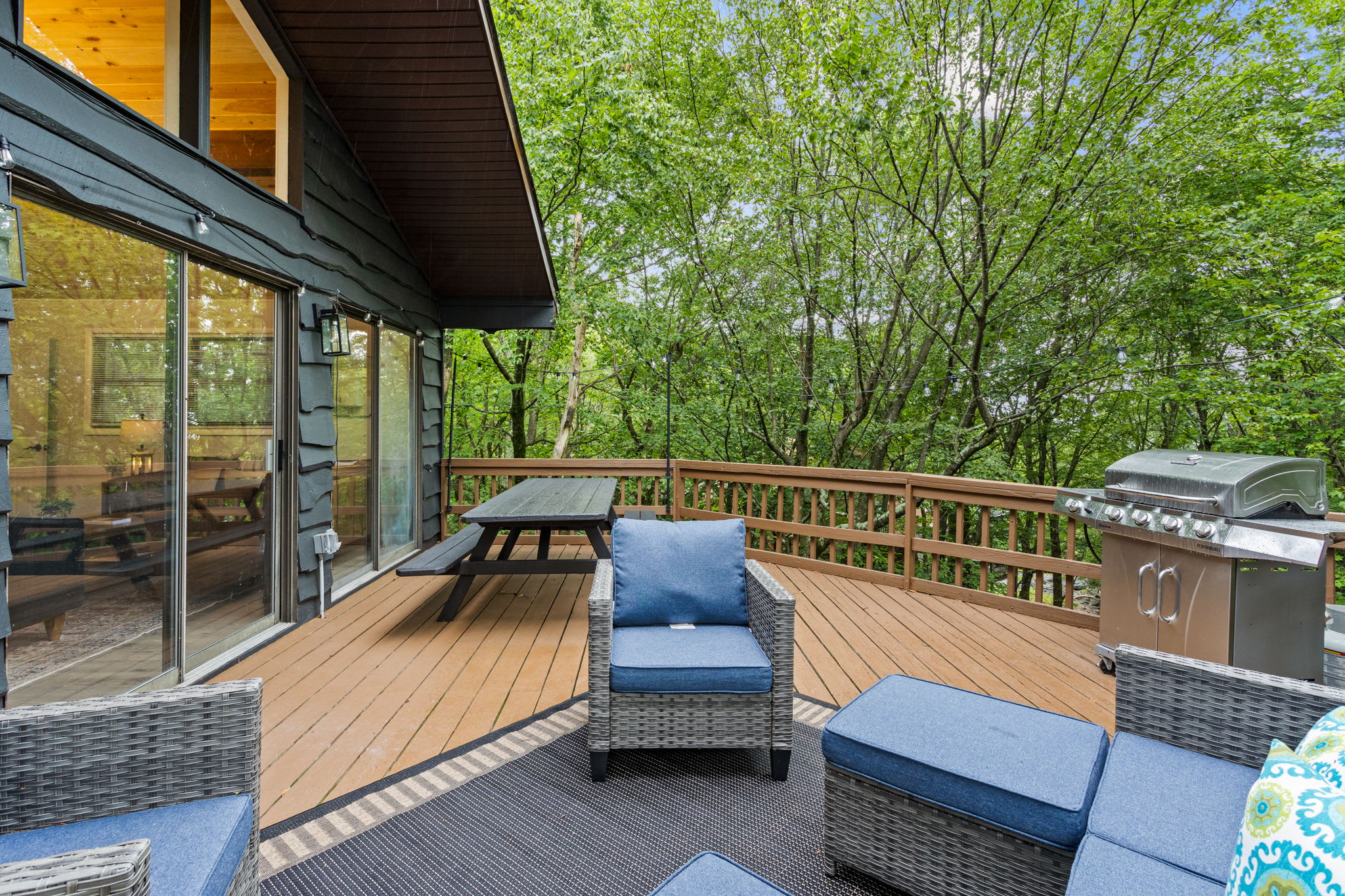 Expansive Outdoor Deck – A cozy lounge area with plush outdoor furniture, a BBQ grill, and scenic forest views.