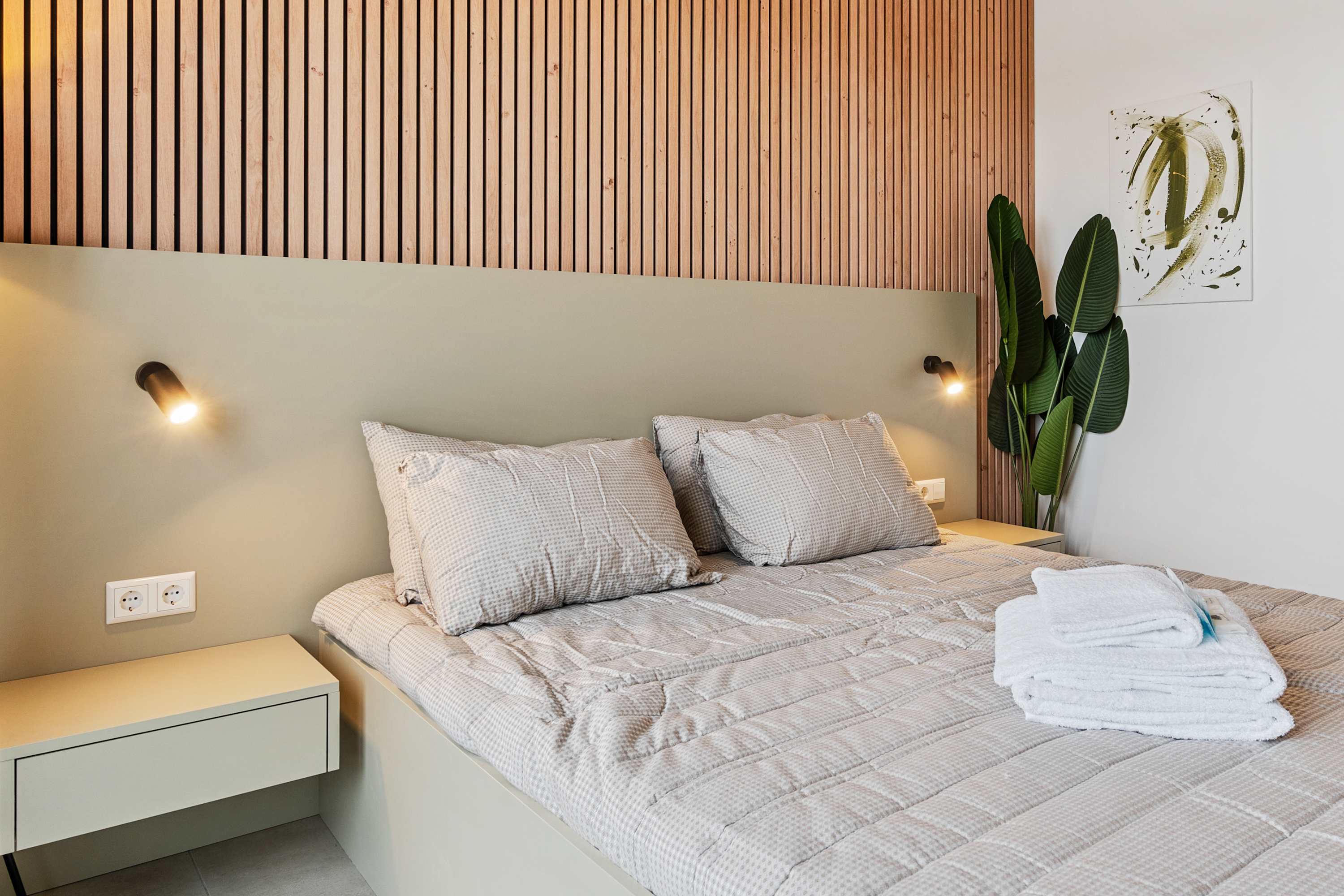 Inviting Living and Sleeping Space – Unwind in a cozy area featuring a queen-sized bed and a sophisticated wooden accent wall.