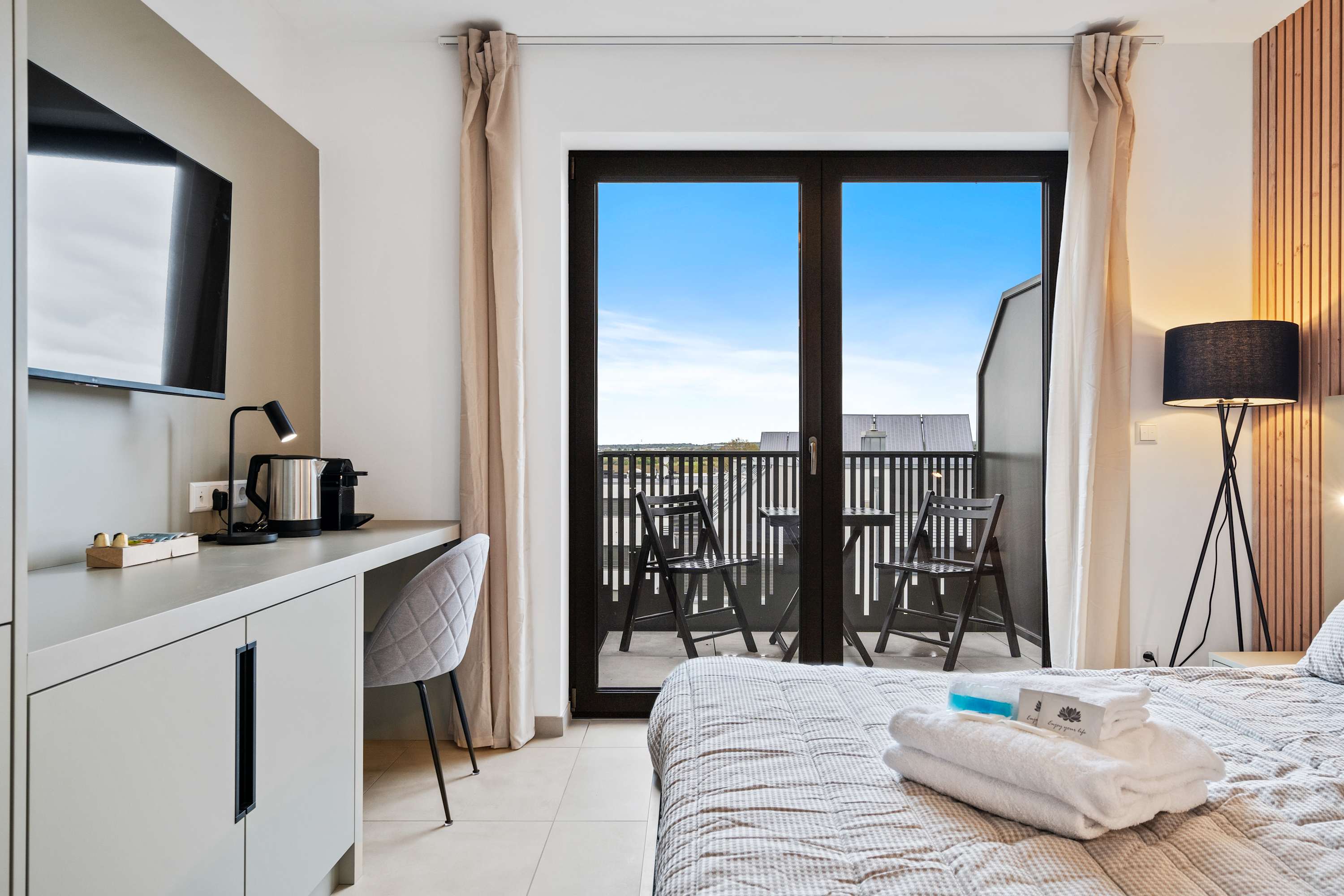 Cozy Living and Sleeping Area – Relax in a comfortable space with a plush queen-sized bed and elegant wooden accent wall.