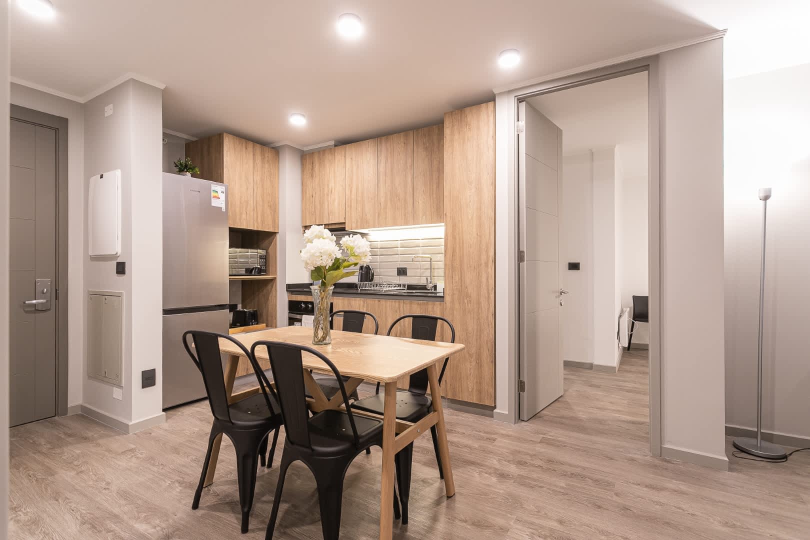 Modern kitchen with sleek wooden cabinets and a cozy dining area, perfect for enjoying meals with family or friends.