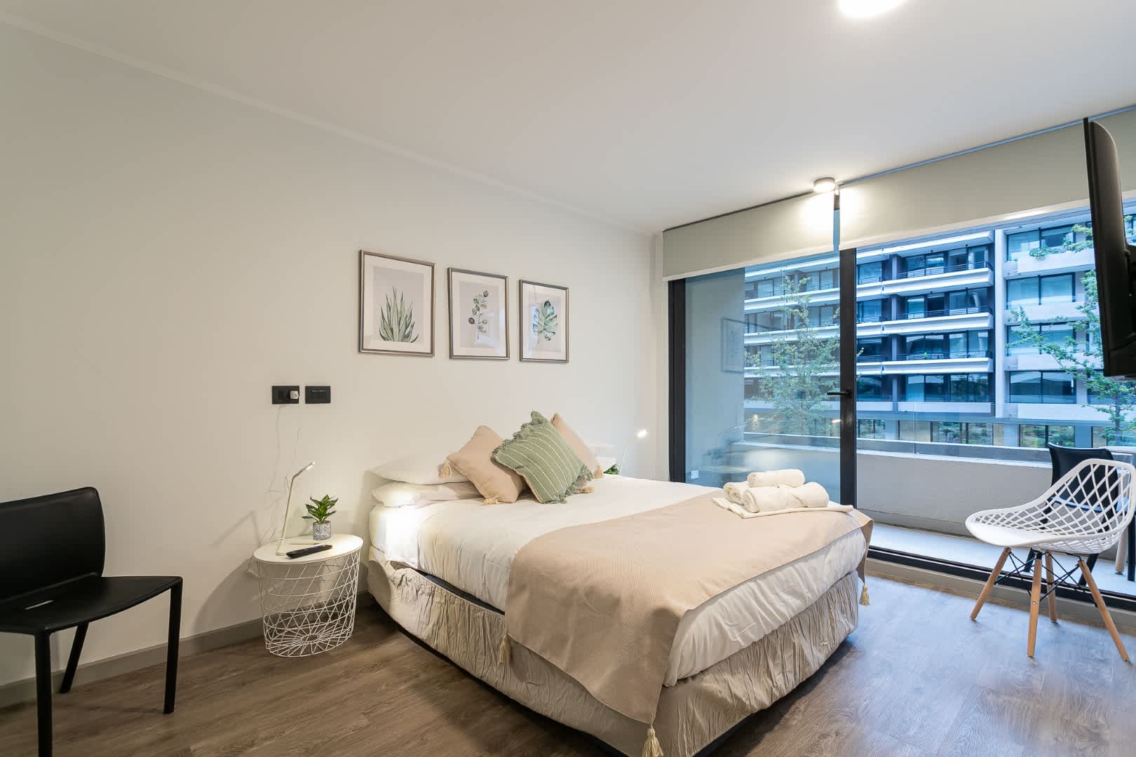 Relax in this stylish bedroom with a comfy bed, chic decor, and a stunning city view from the large window.