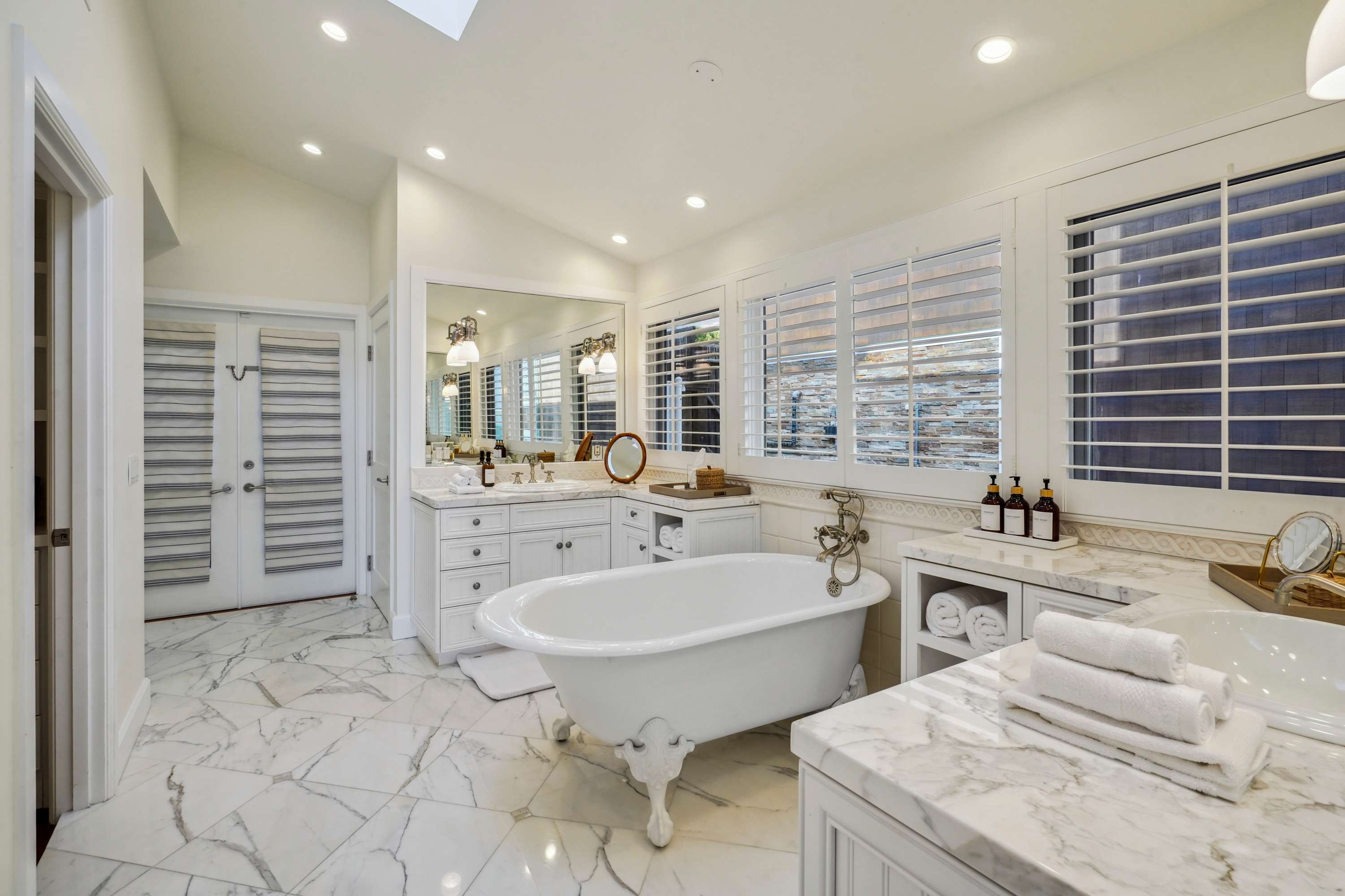 A freestanding clawfoot tub set against marble floors.