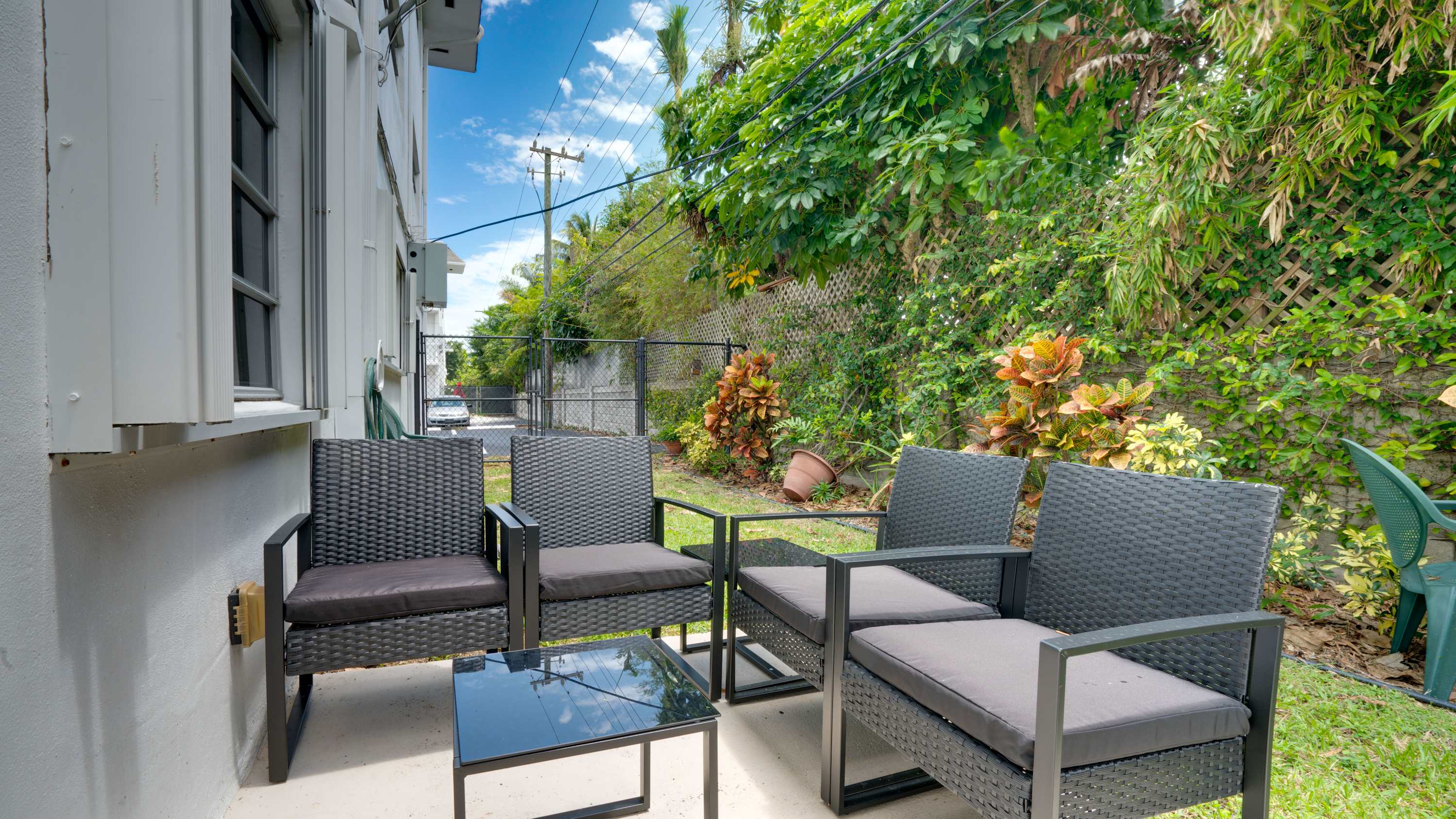 Relax in this cozy outdoor patio surrounded by lush greenery, perfect for morning coffee or evening chats.