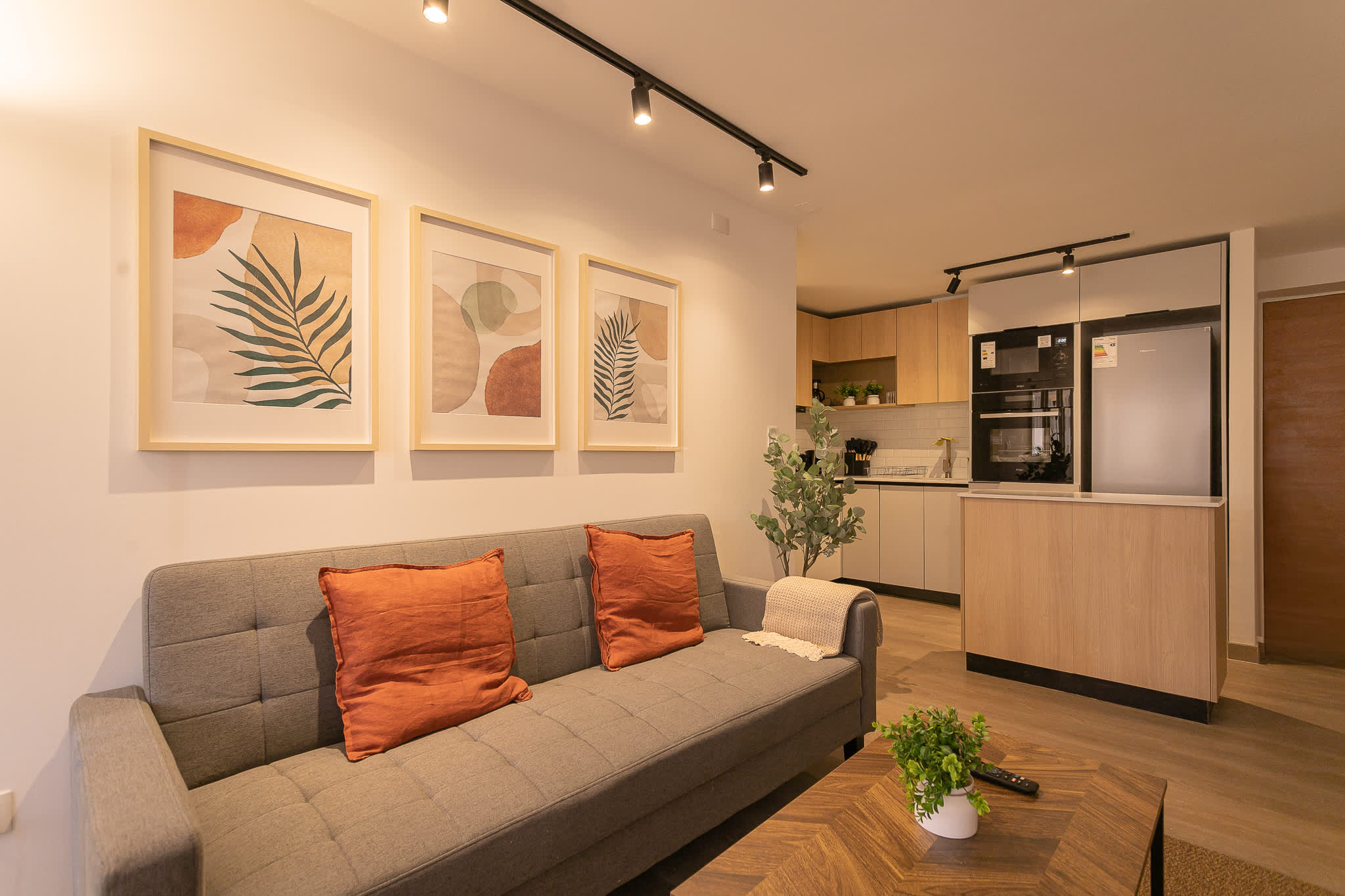 Relax in this stylish living area with modern decor, cozy seating, and a sleek open kitchen—perfect for unwinding or entertaining.