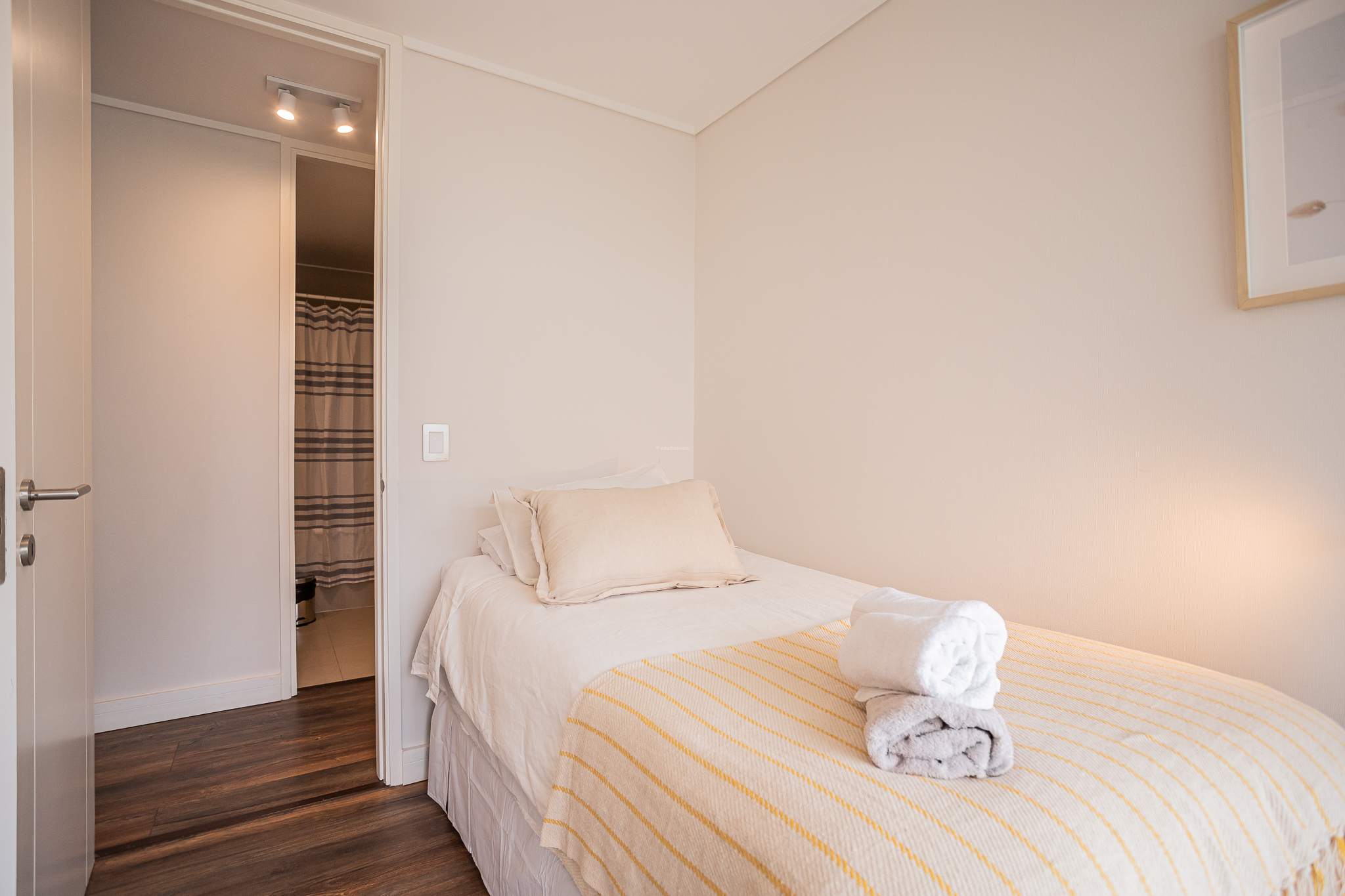 Cozy bedroom with soft lighting and direct bathroom access, perfect for a relaxing stay.
