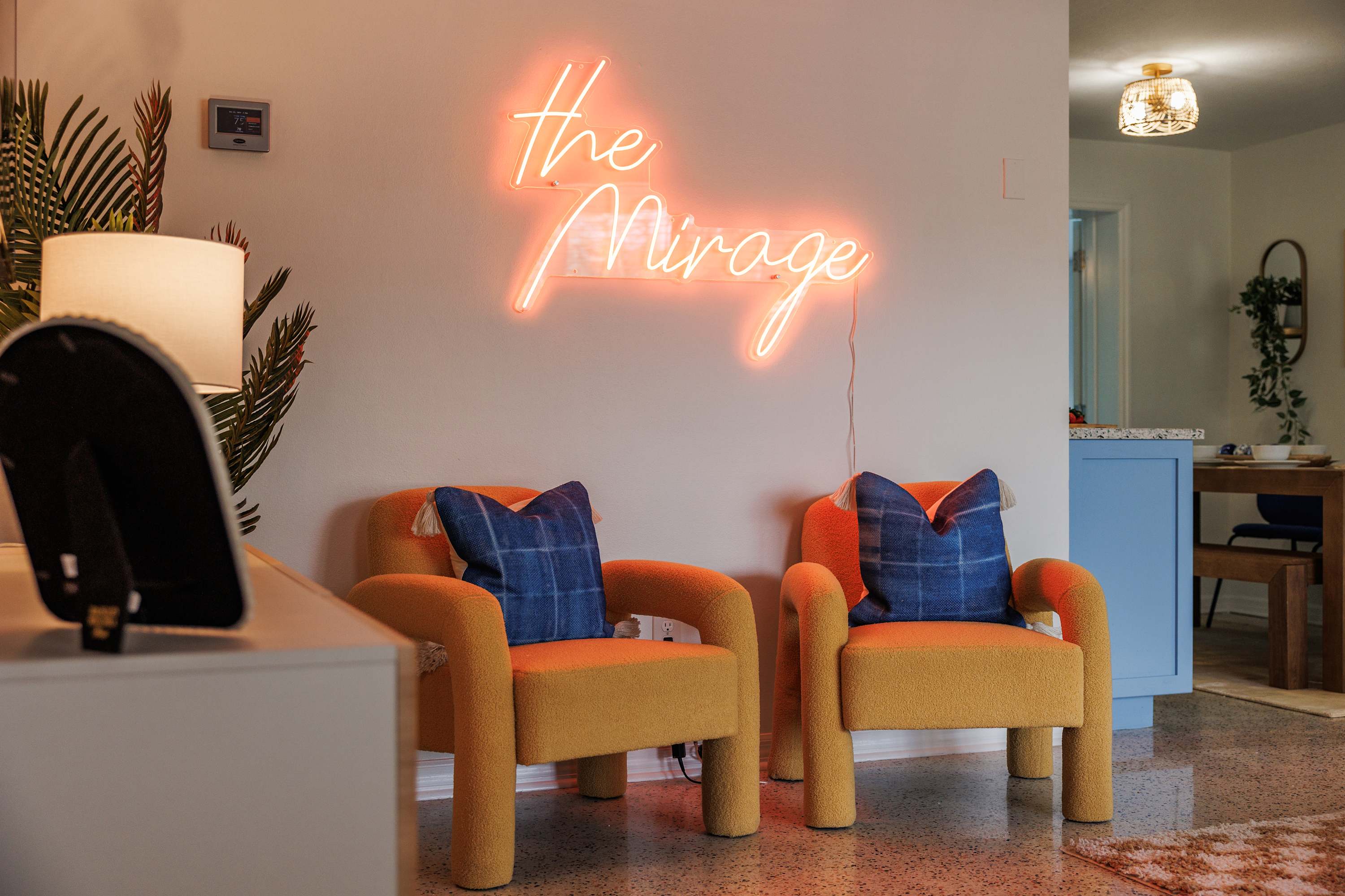 Cozy corner w/ chairs and a glowing neon sign adding playful vibes.