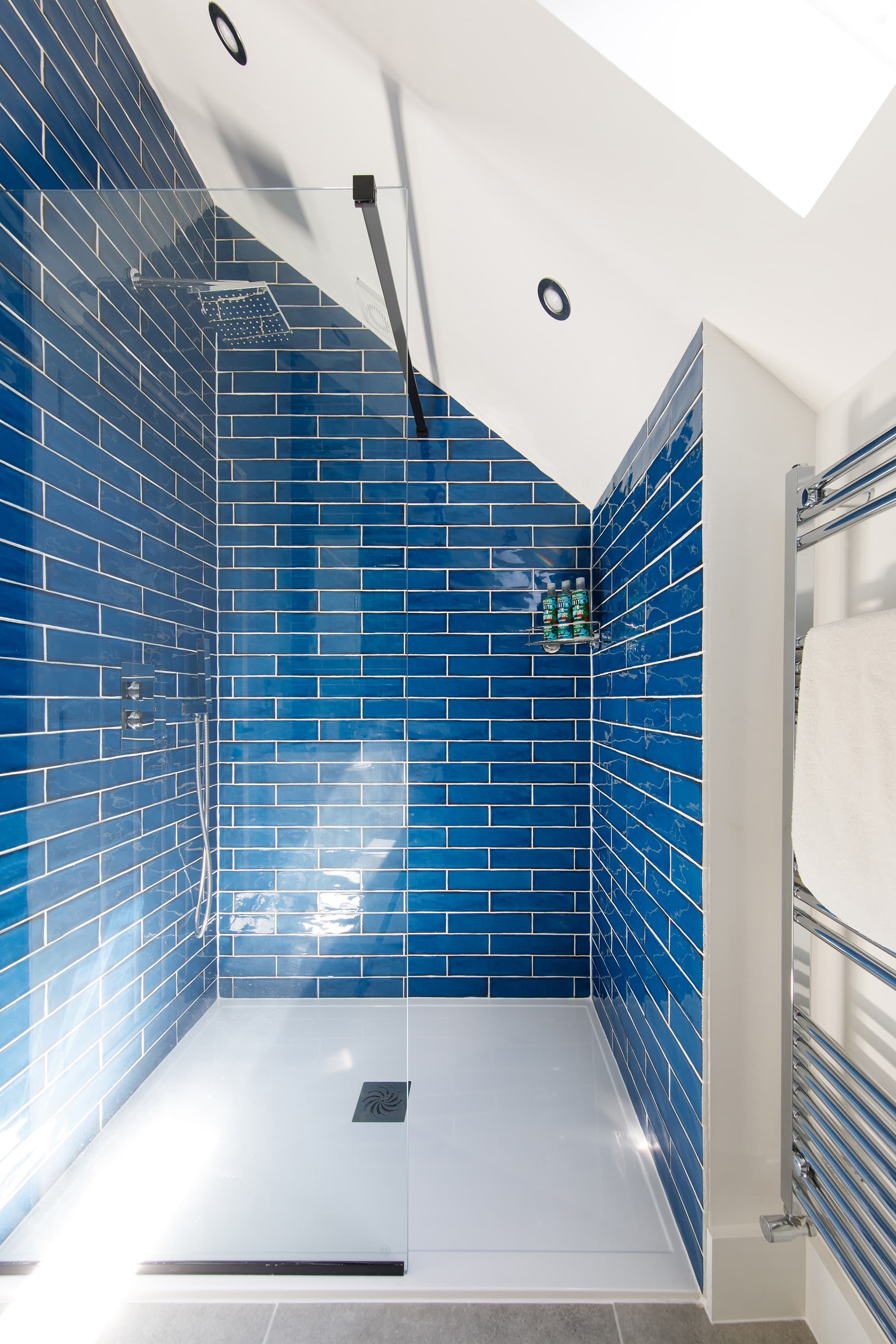 The large shower is tiled with beautiful ocean blue tiles.