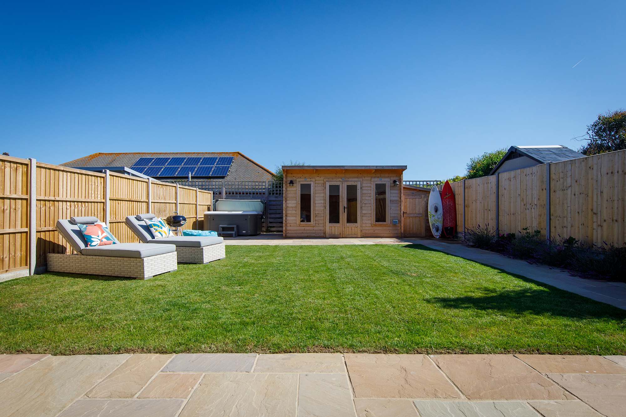 Relax in the pristine garden, which has a patio, grassy area with sun loungers and a hot tub!