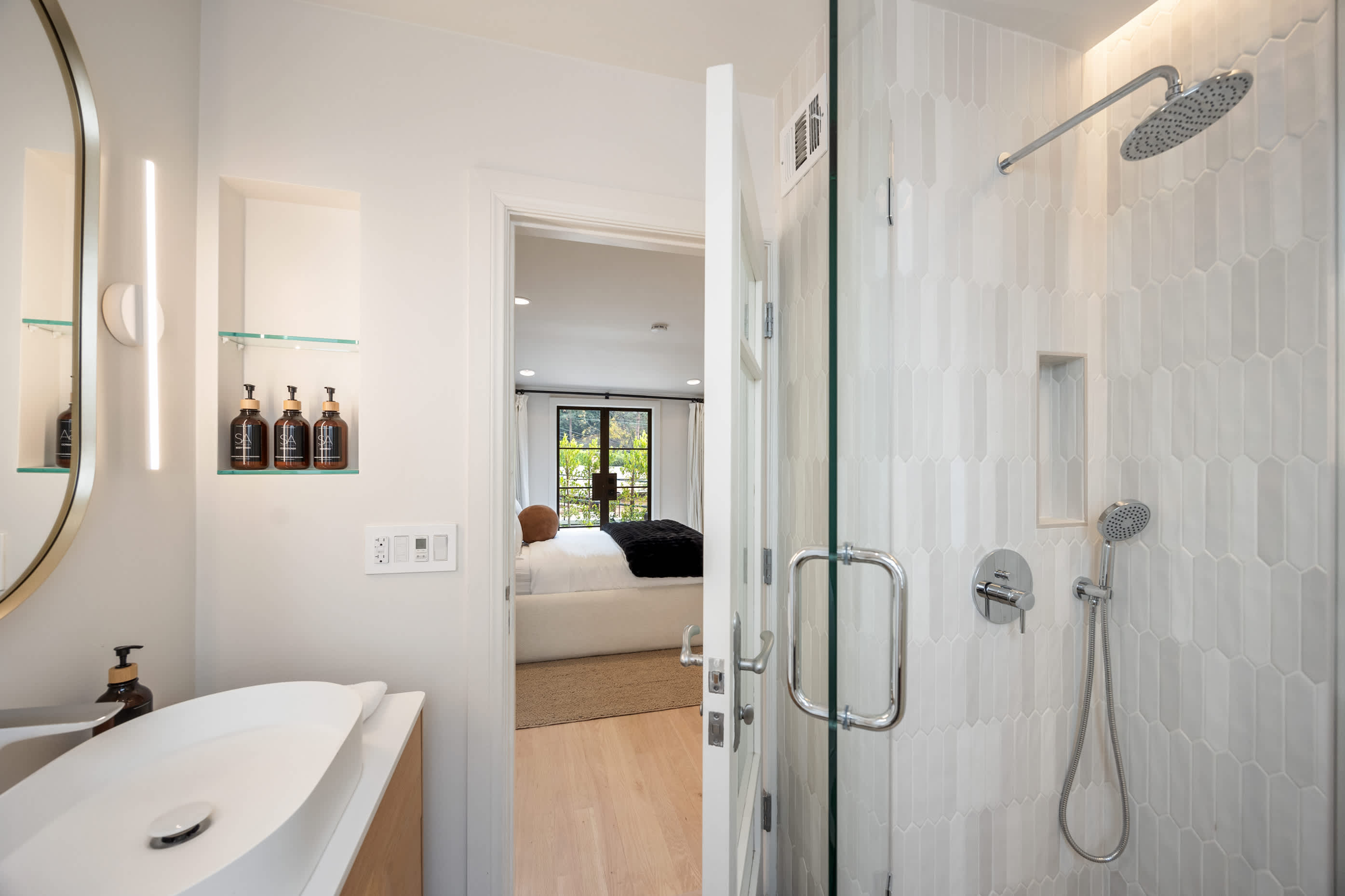 Walk-in shower with modern tilework, rainfall showerhead, and built-in shelving.