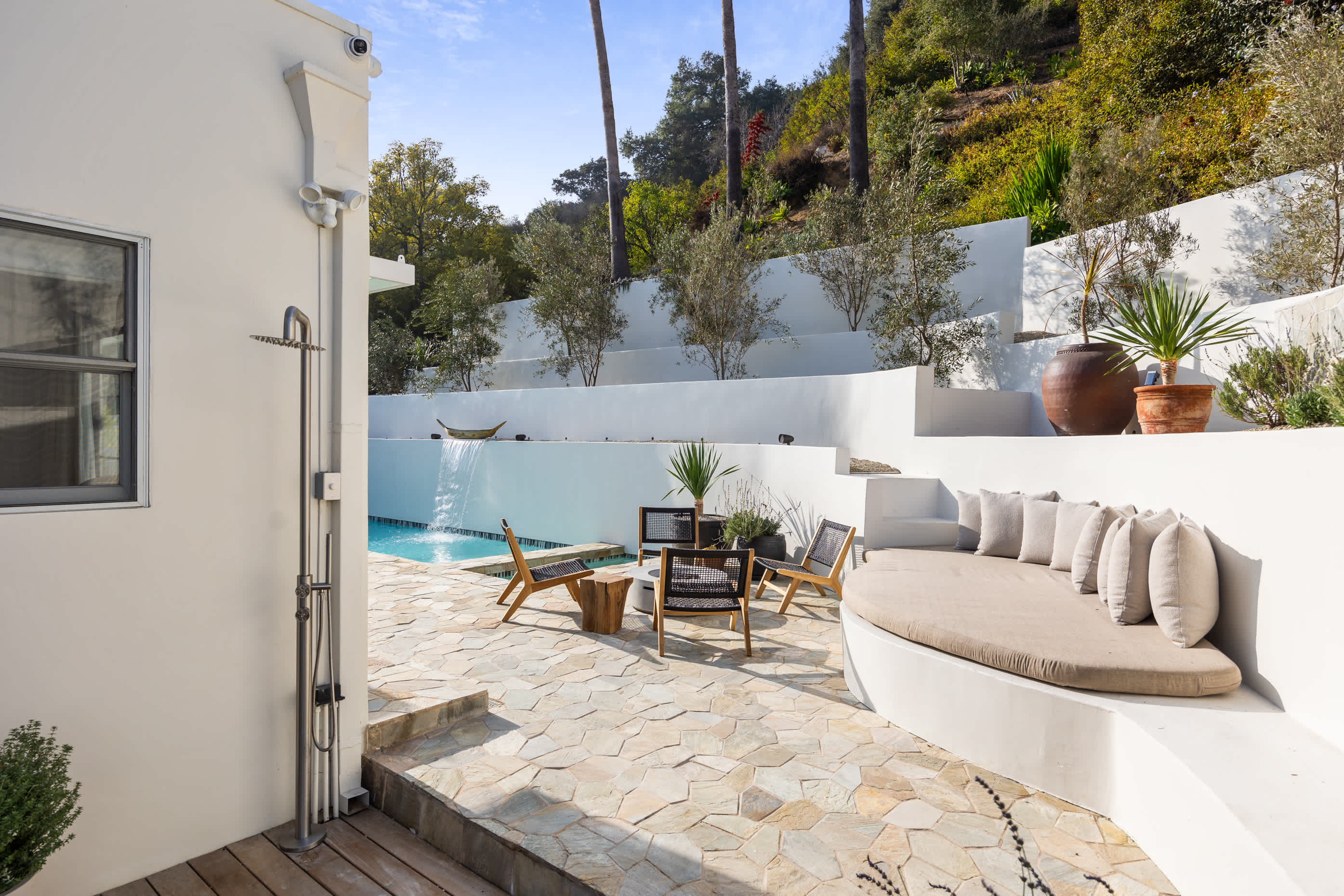 Soft curves and textured stone meet plush seating by the sunlit pool.