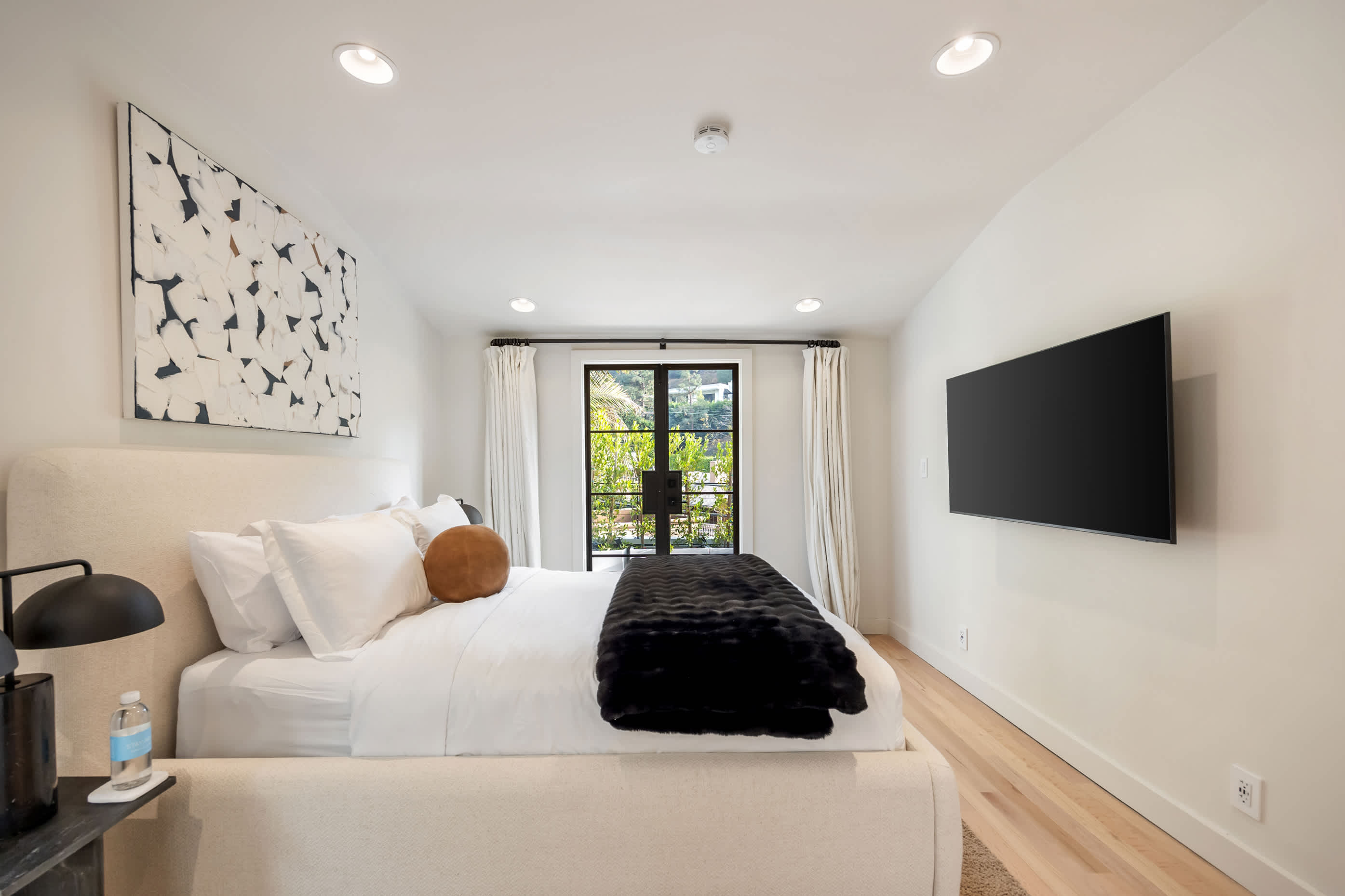 Crisp linens and sunlit garden views create a bedroom of serene comfort.