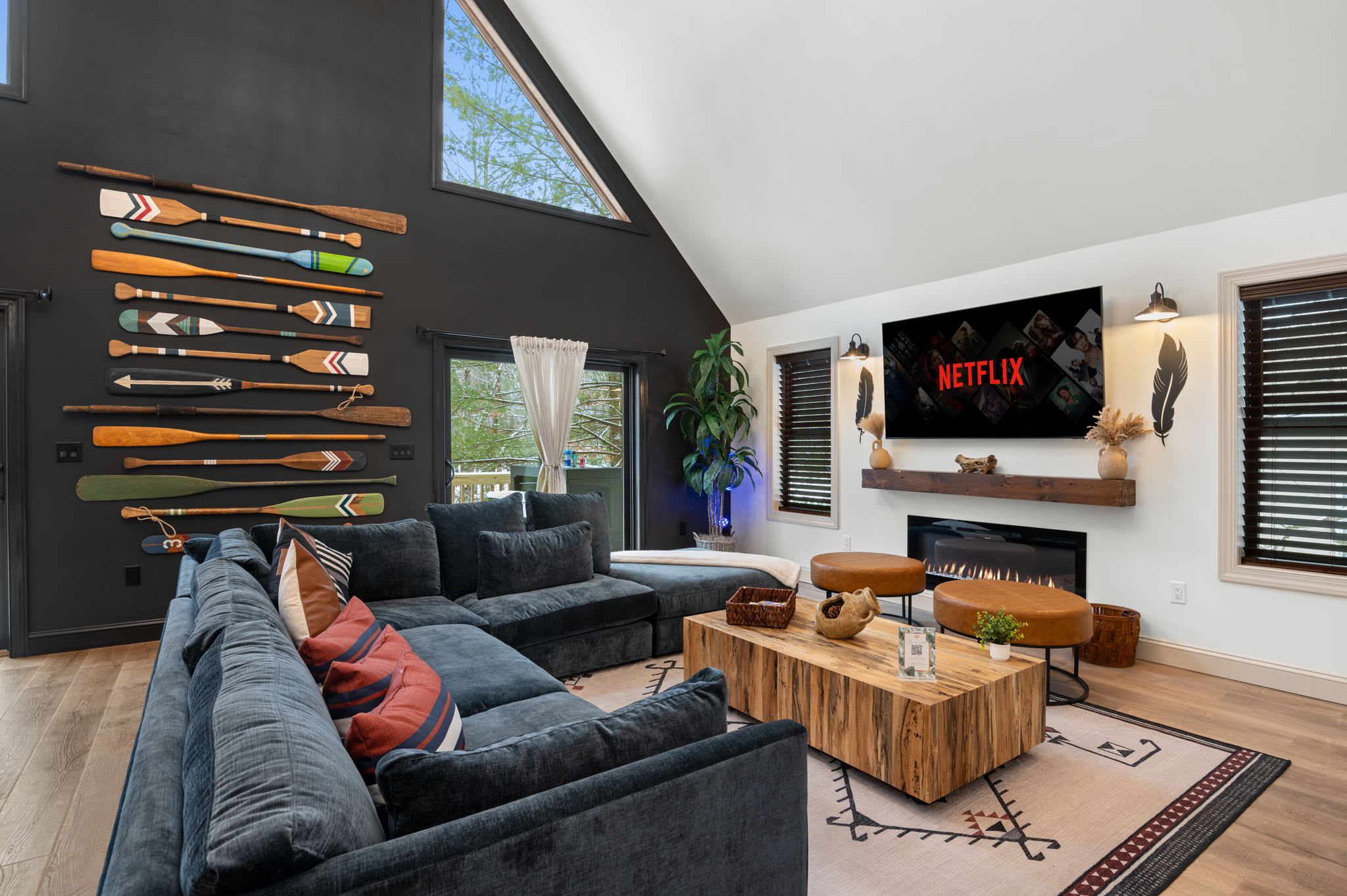 A spacious sectional faces a fireplace and TV, with vaulted ceilings and large windows flooding the room with natural light, ideal for relaxed gatherings.
