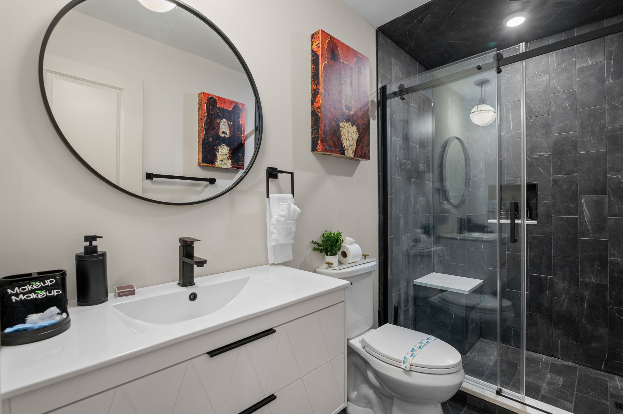 Step into a modern, spa-inspired bathroom with sleek black and white finishes, a spacious vanity, and a glass-enclosed rainfall shower. Perfect for unwinding after a long day of adventures.