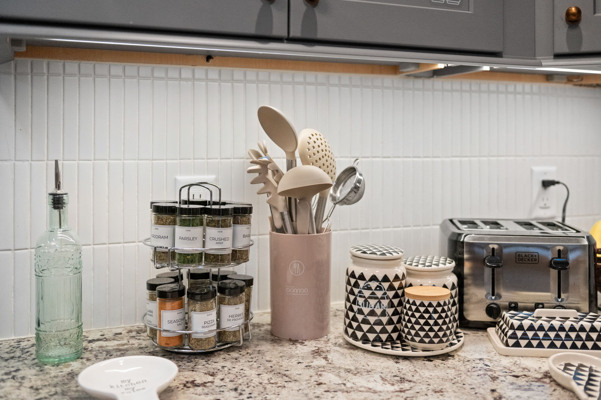 The countertop is ready for home cooking, complete with essential spices, utensils, and a trusty toaster.