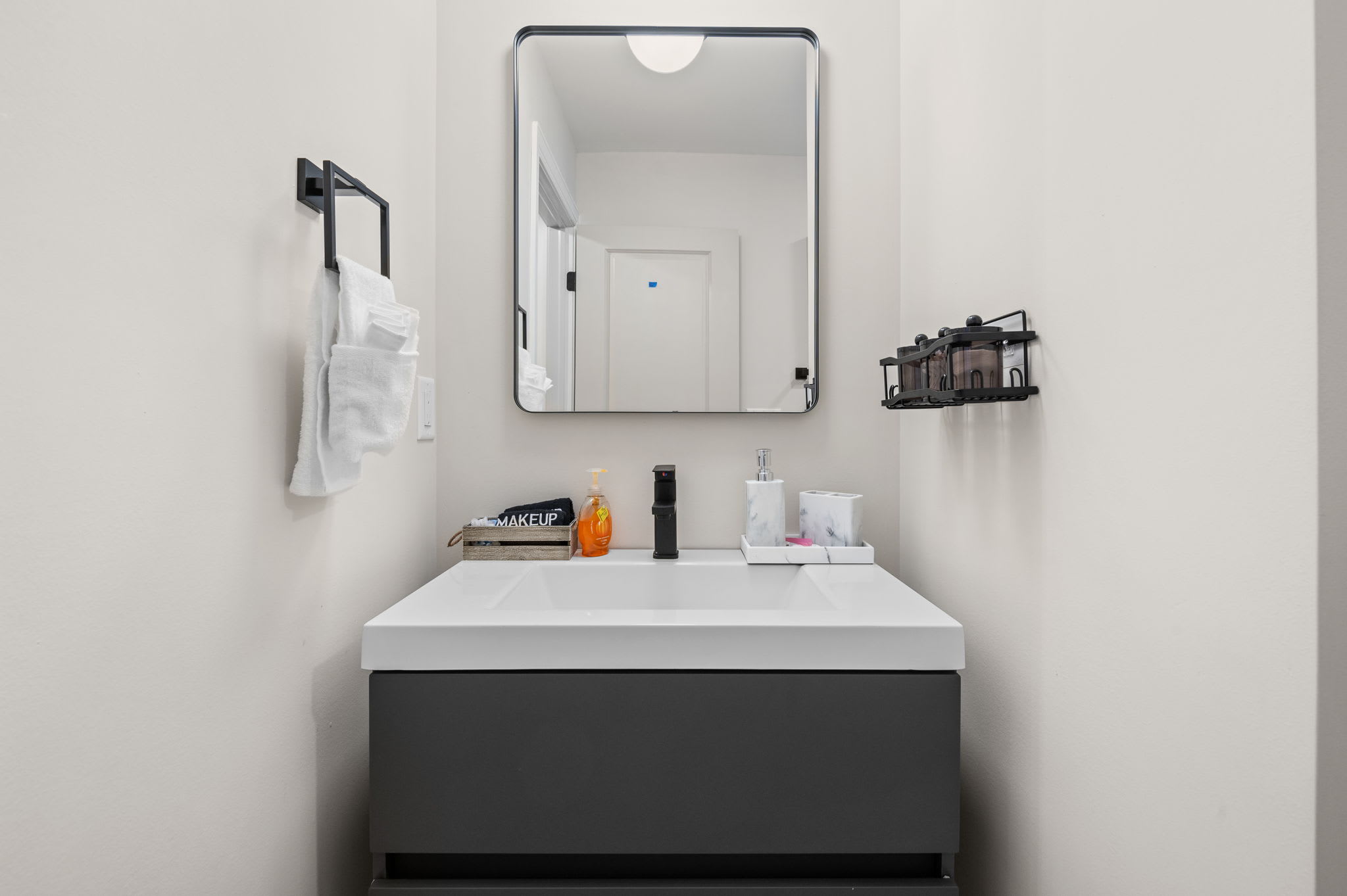 A beautifully designed vanity space with a modern mirror, fresh towels, and all the little details to help you feel at home.