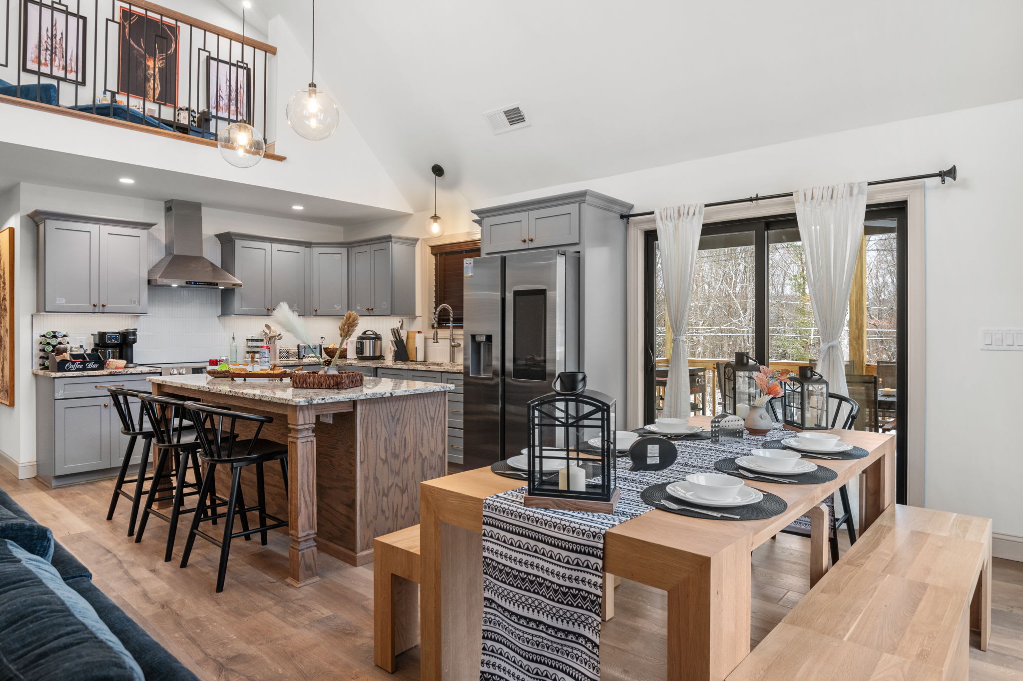 From the kitchen to the dining area, the open floor plan keeps conversation flowing, framed by large windows and vaulted ceilings.