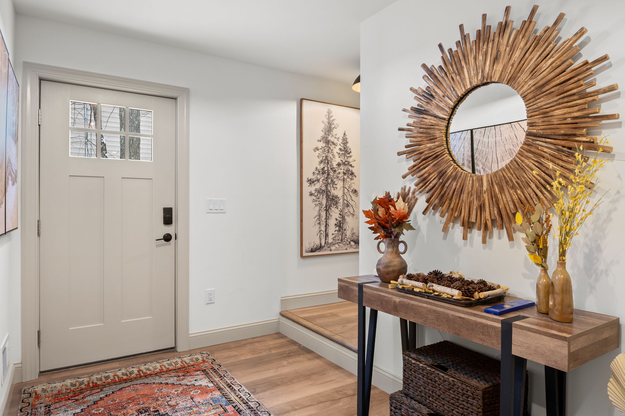 The entryway greets you with a sunburst mirror and rustic accents, setting a welcoming tone that blends modern flair with nature’s warmth.