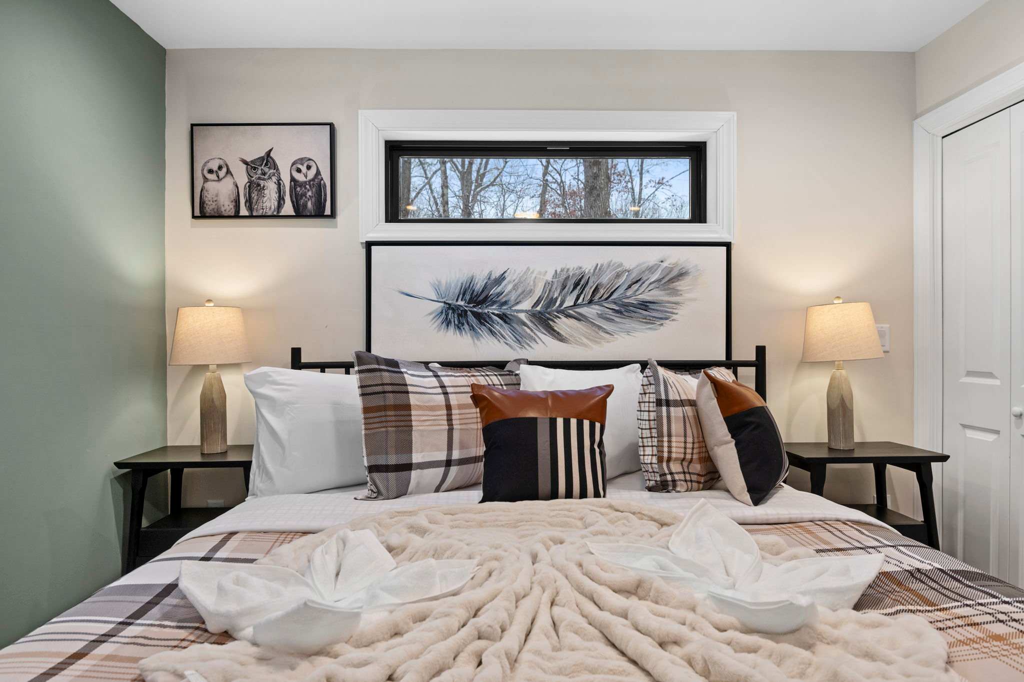 Plaid linens, warm lighting, and feather-inspired art set a soothing tone, inviting you to settle in for a restful sleep.