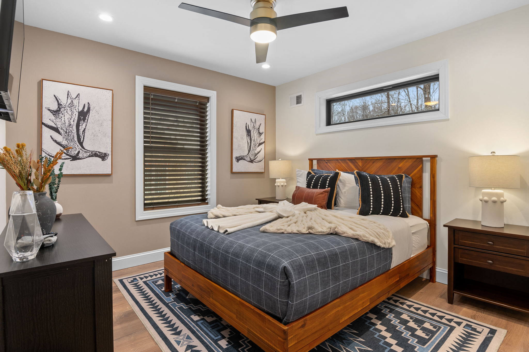 A cozy and stylish retreat with a warm wooden bed, soft neutral bedding, and rustic decor. Natural light and thoughtful details make this the perfect place to unwind.