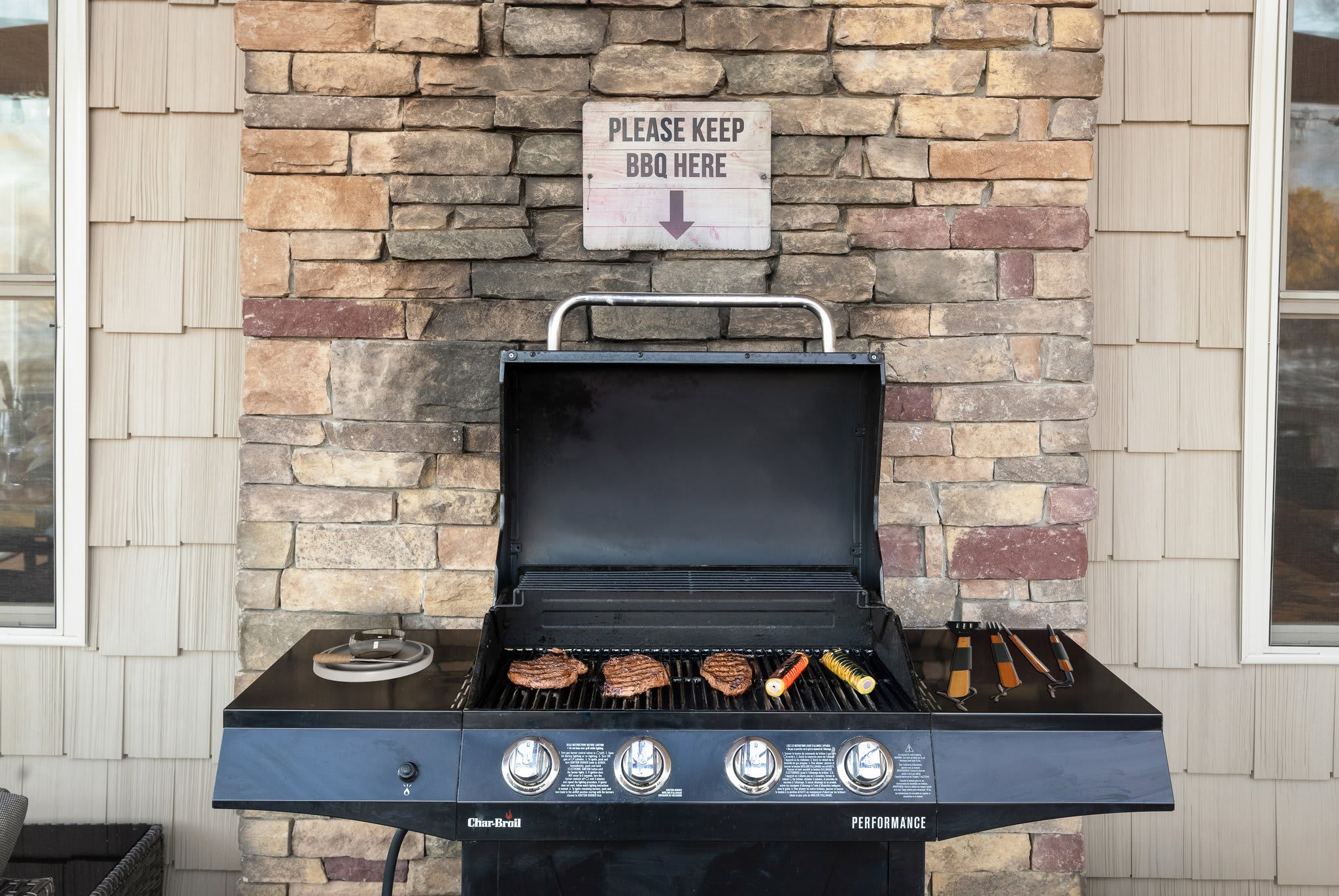 BBQ dreams come true with a grill sizzling under a “Please keep BBQ here” sign, built into a stone wall nook.