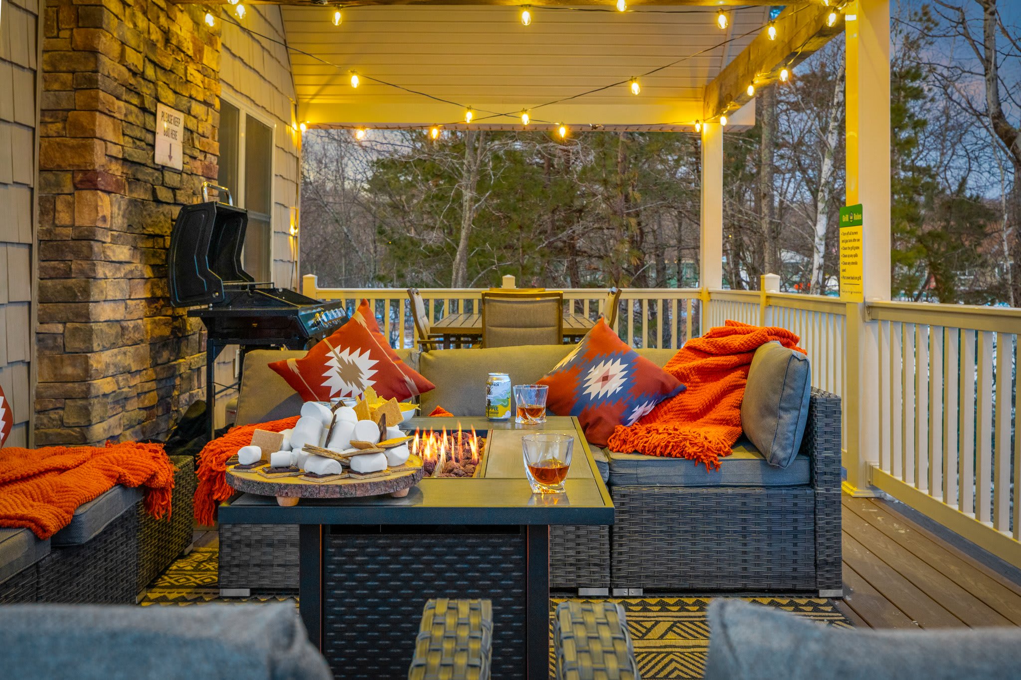 Another angle of the same inviting setup, wicker seating, flickering flames, and a grill tucked in the corner.