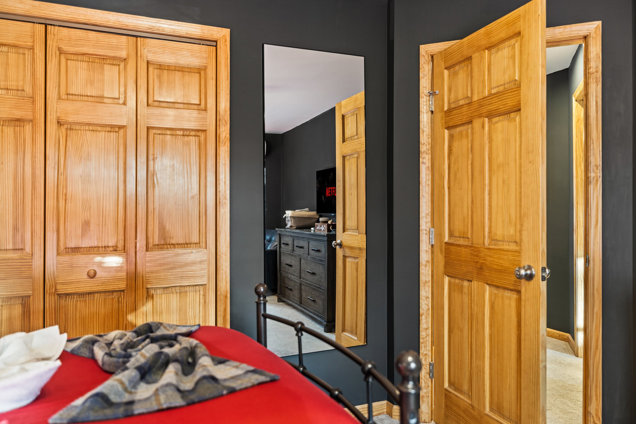 A warm shot of beds and natural wood closet doors, peeking into the hallway with cozy cabin vibes.