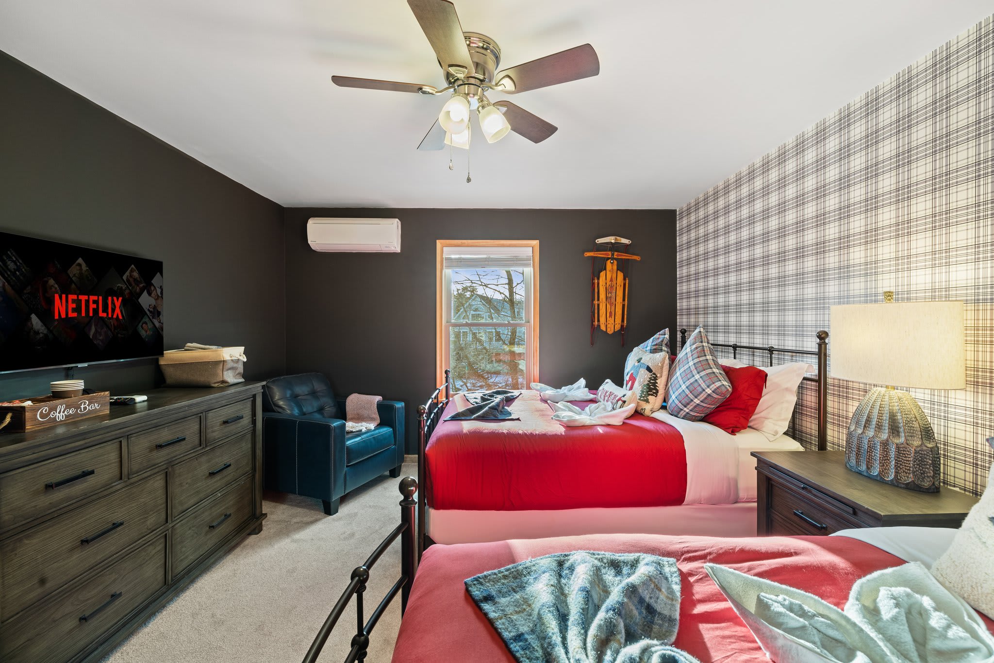 Two bright red beds, cozy throws, and a mounted TV make this perfect for a sibling sleepover or movie night.
