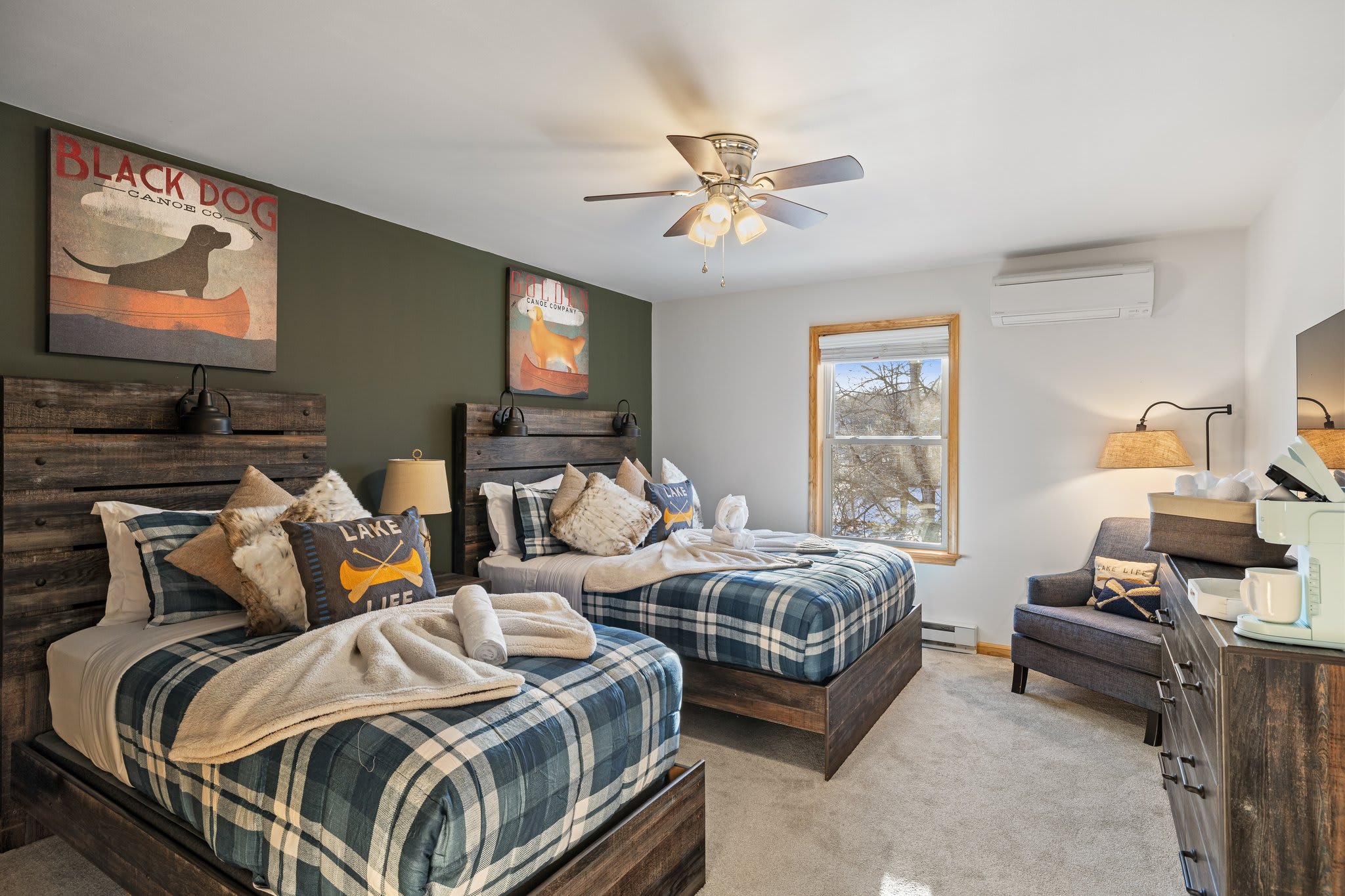 Rustic wood headboards, plaid bedding, and soft lighting give this room a lodge-style, retreat energy.